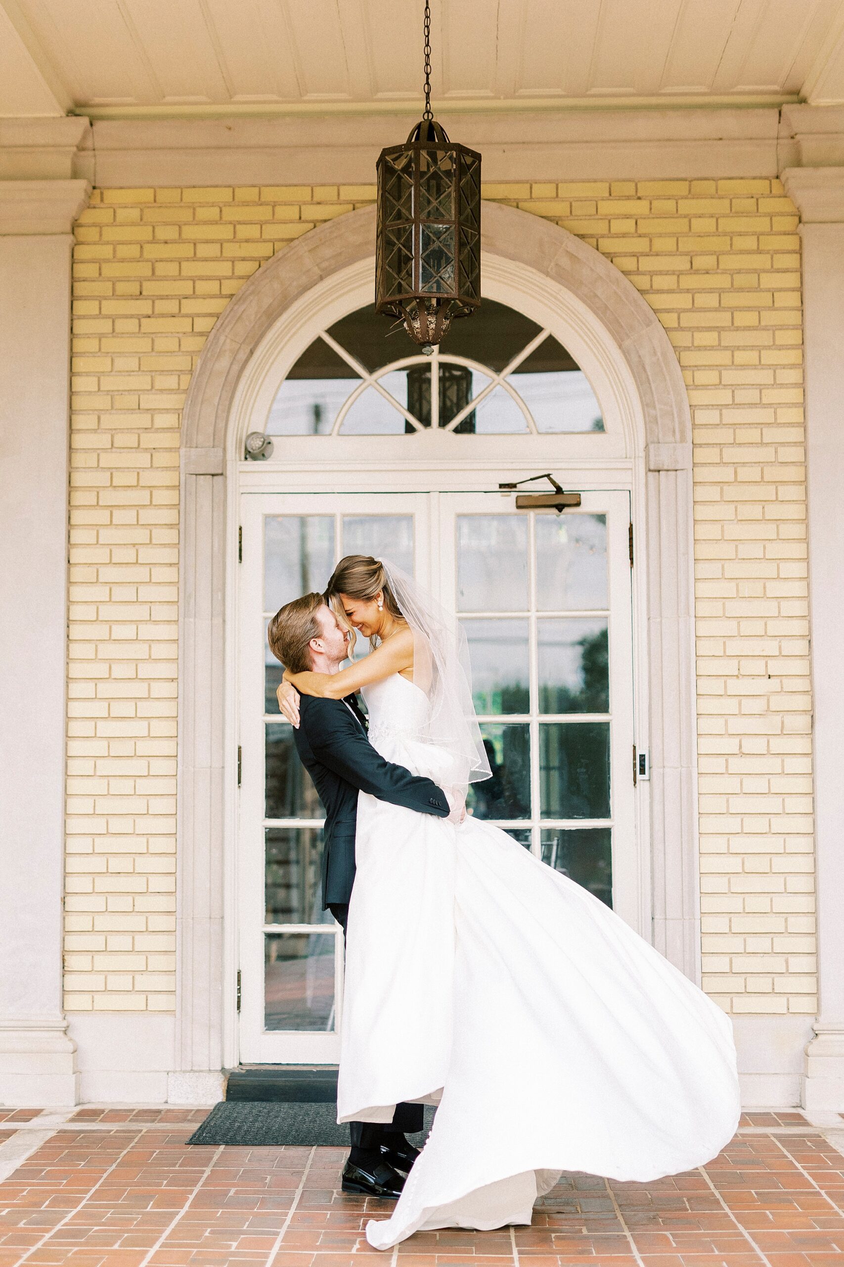 groom lifts up bride in front of tall window at Separk Mansion