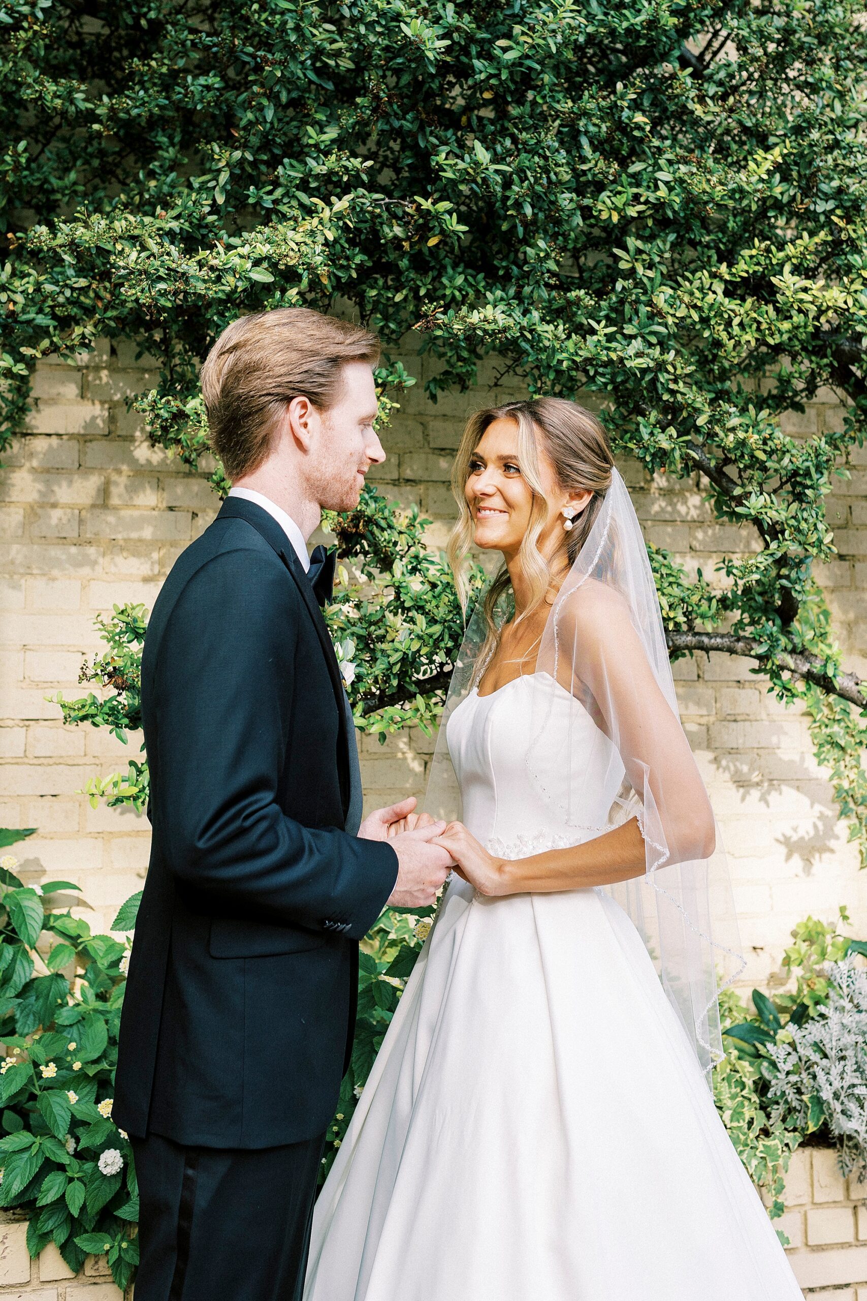 bride and groom hold hands smiling at each other