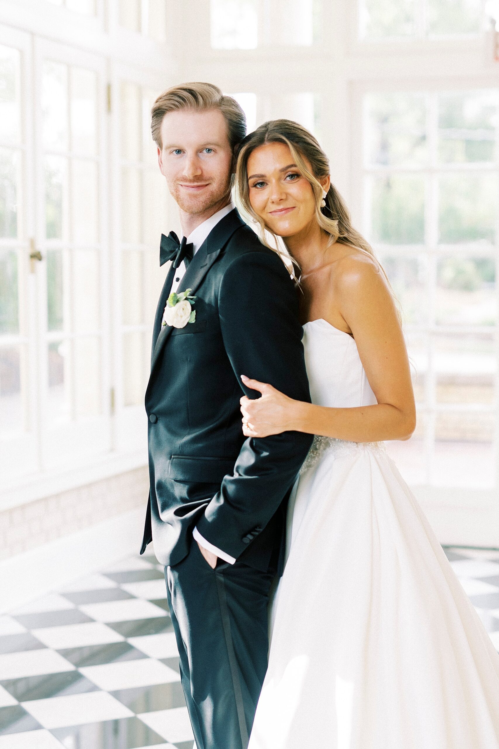 bride leans on groom's back during portraits in sunroom at Separk Mansion