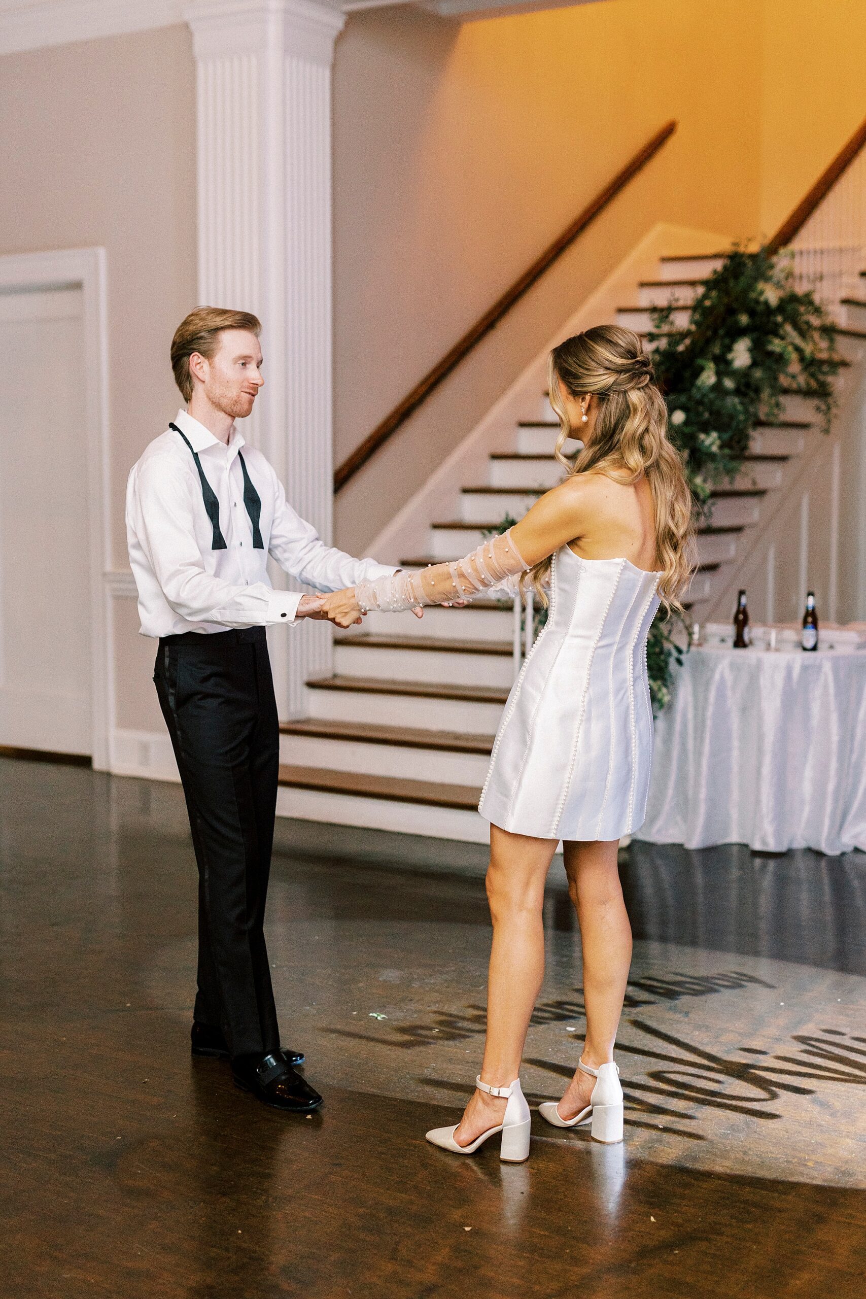 groom dances with bride in short white party dress