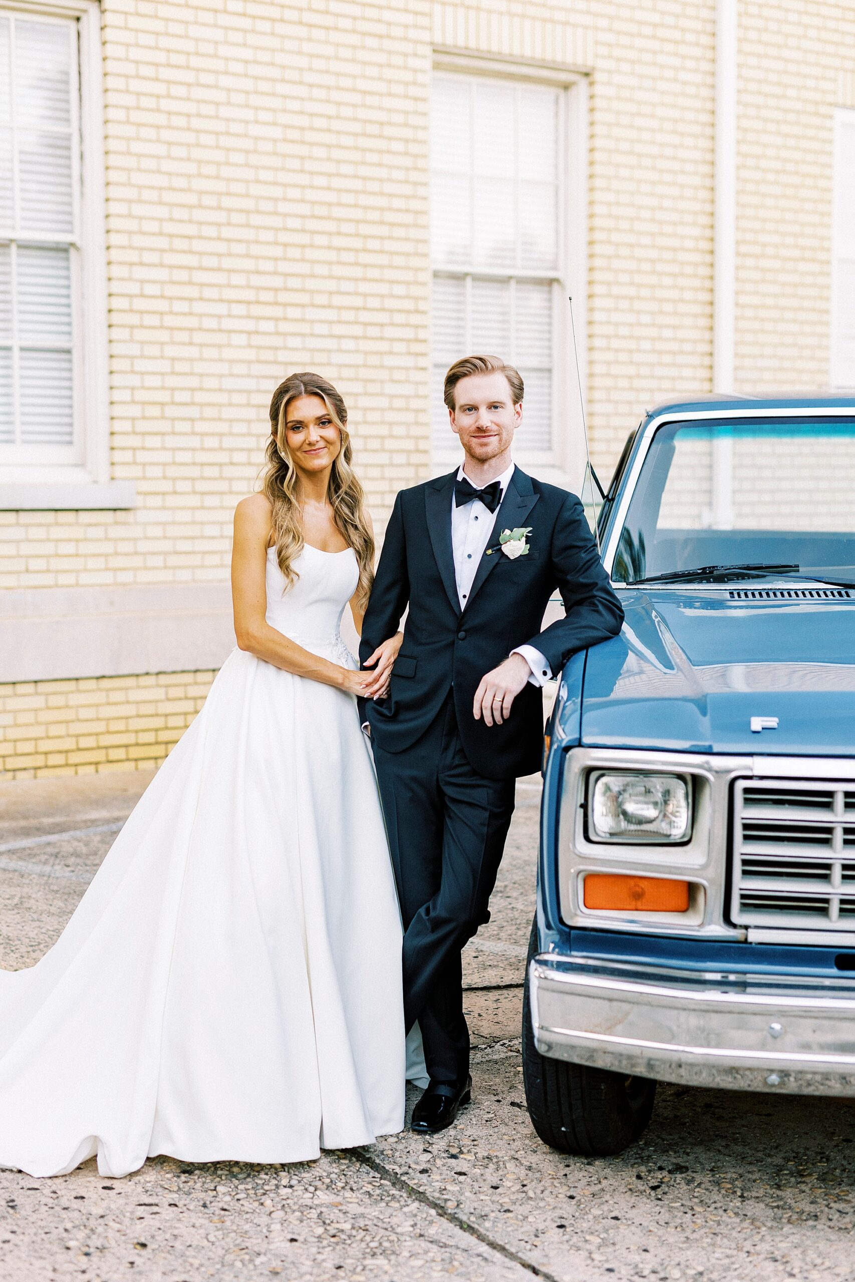 bride and groom lean against classic blue truck outside Separk Mansion