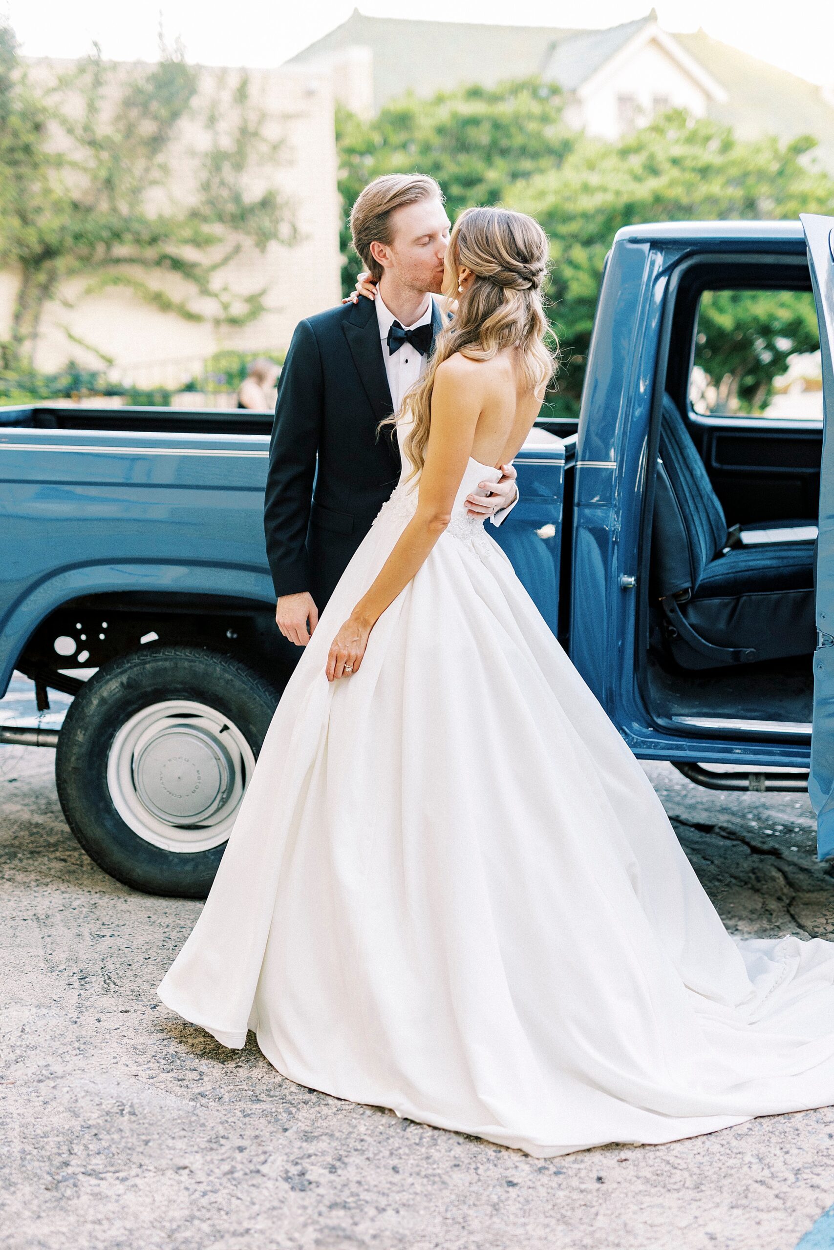 bride and groom kiss by classic blue truck