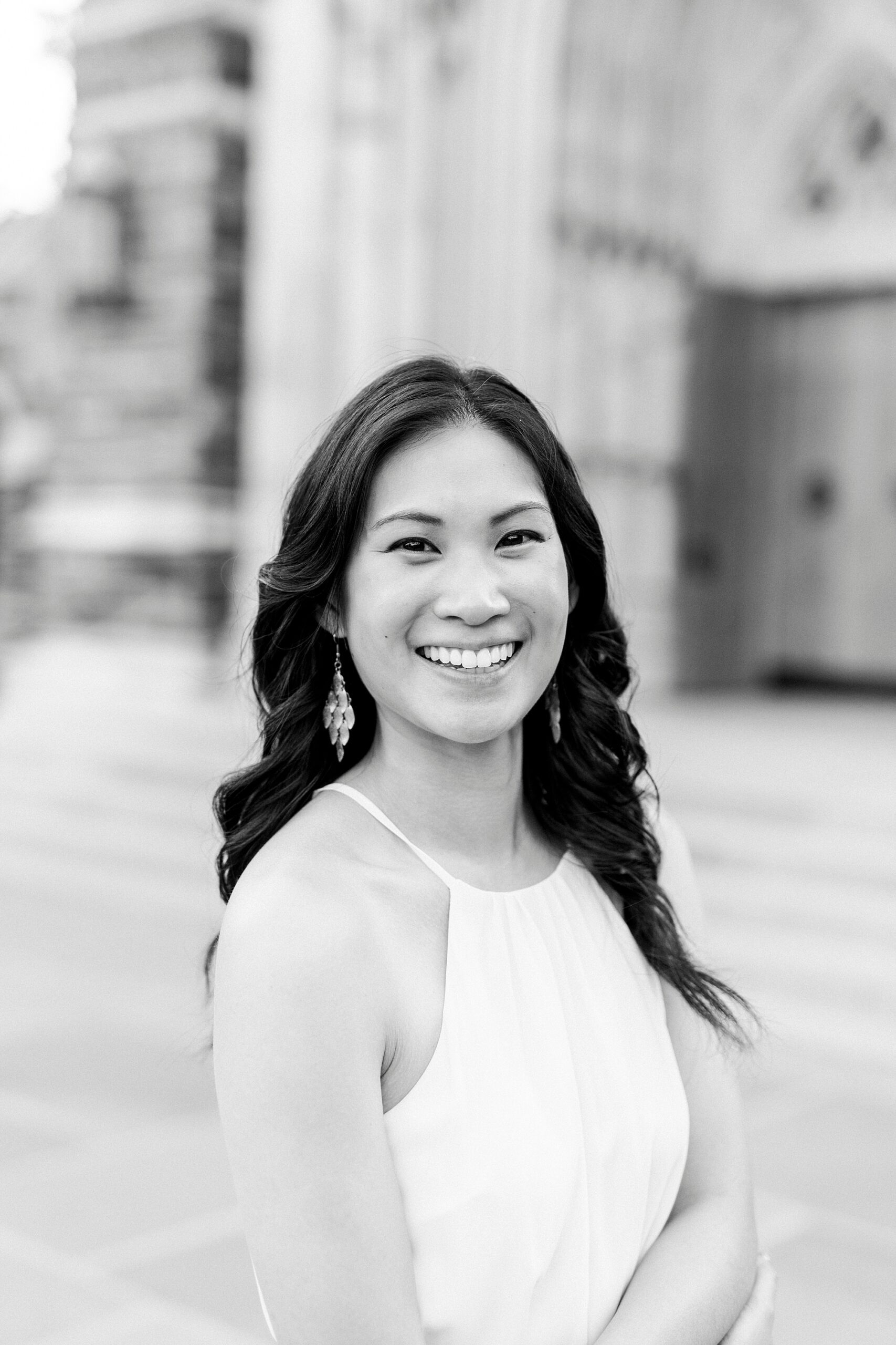woman smiles in white dress in front of Duke University chapel