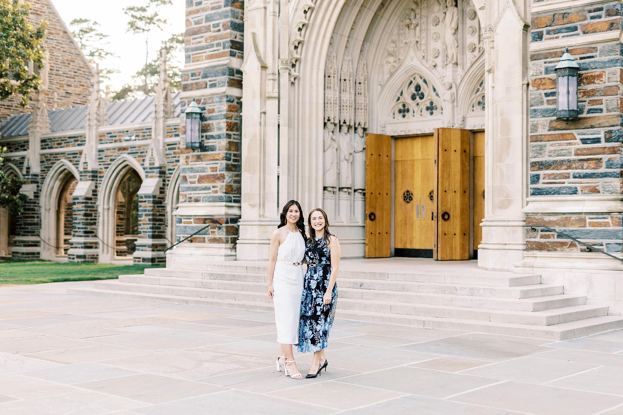 two friends stand in front of chapel's wooden doors at Duke University