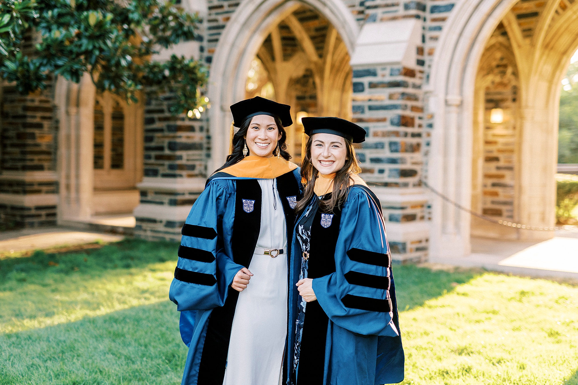 women hug in blue and black doctorate robes and hat