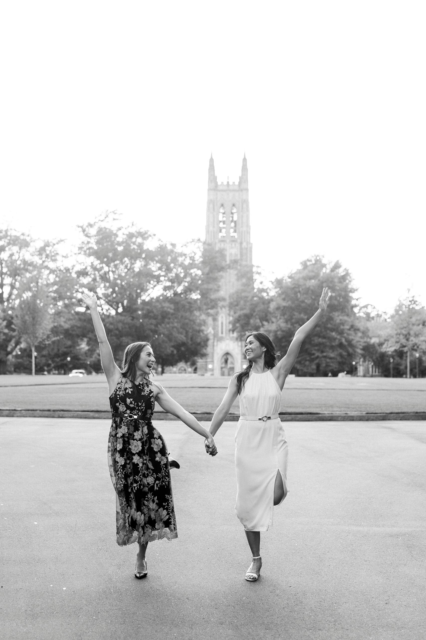 women smile holding hands and cheering during graduation portraits at Duke University