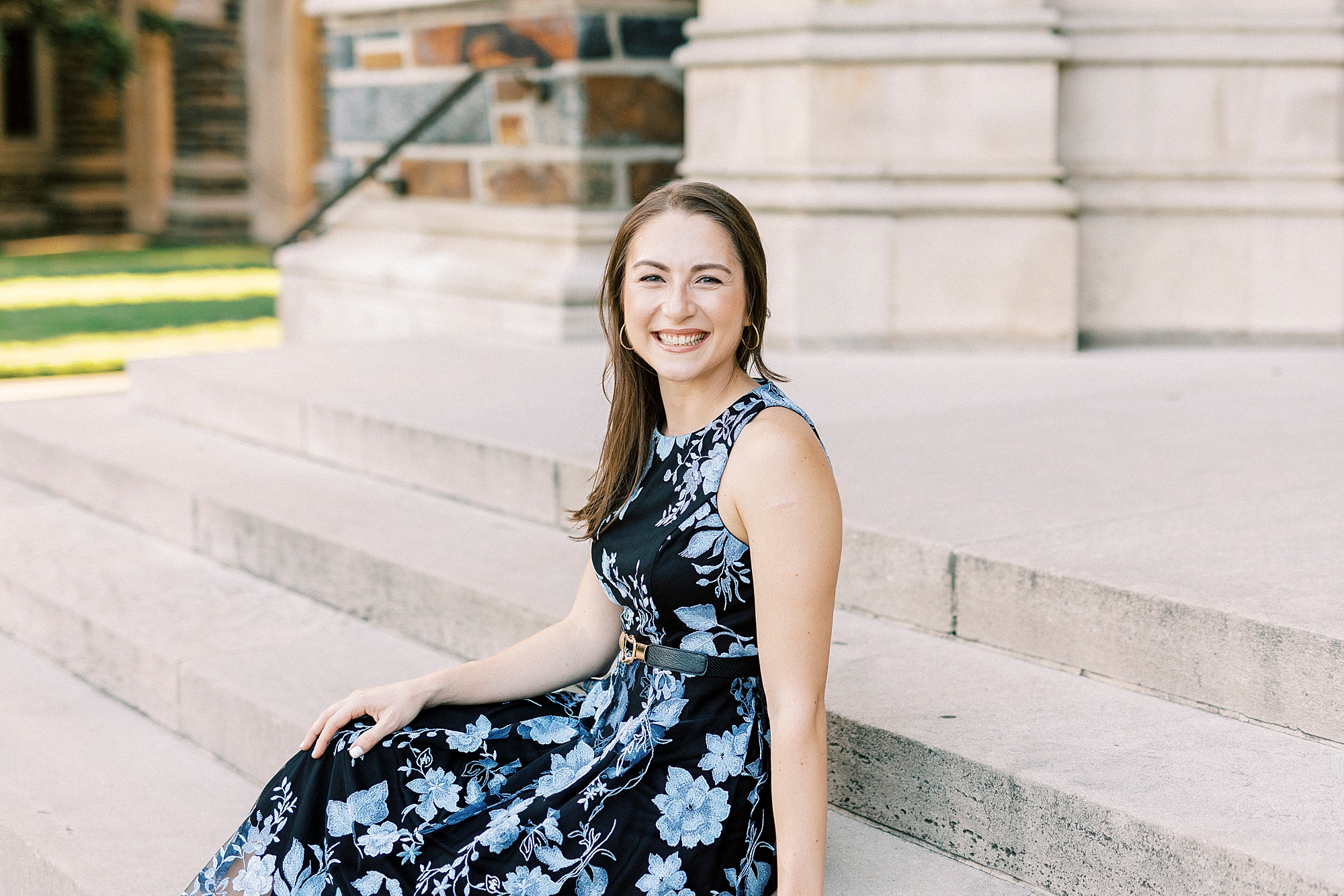 woman sits on steps in blue and black floral dress