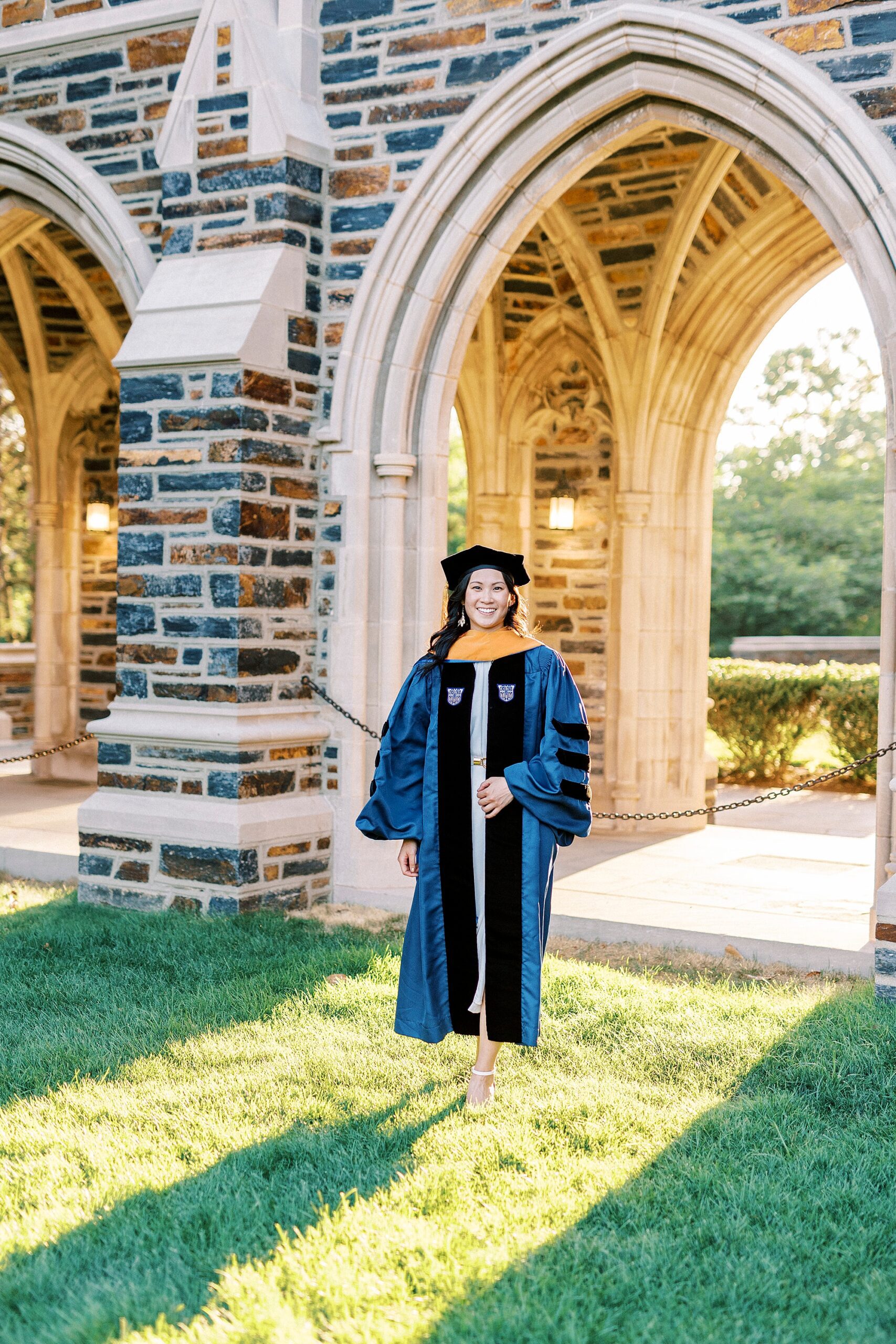woman walks in blue and black robes and hats at Duke University