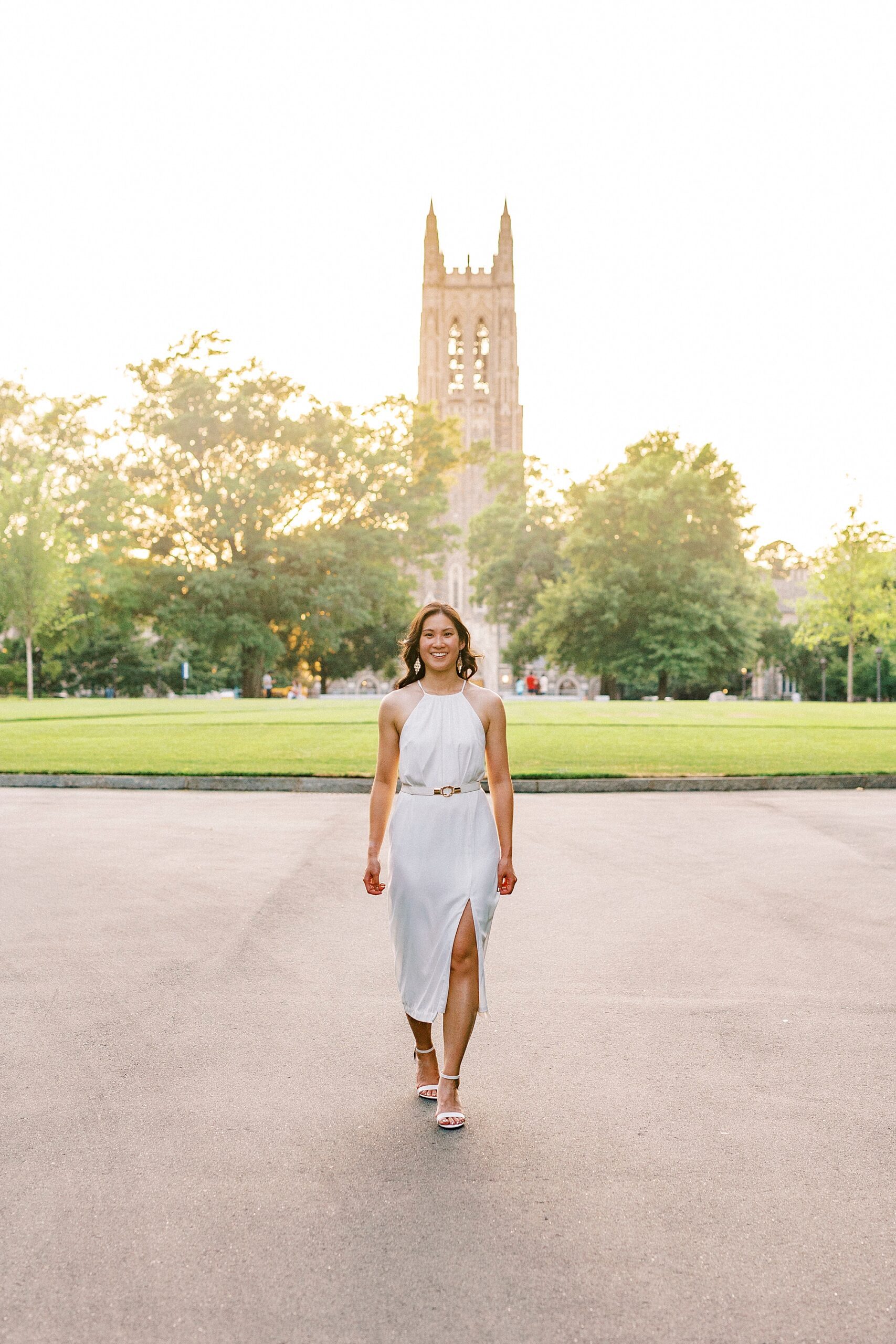 woman in white dress walks on pathway at Duke University