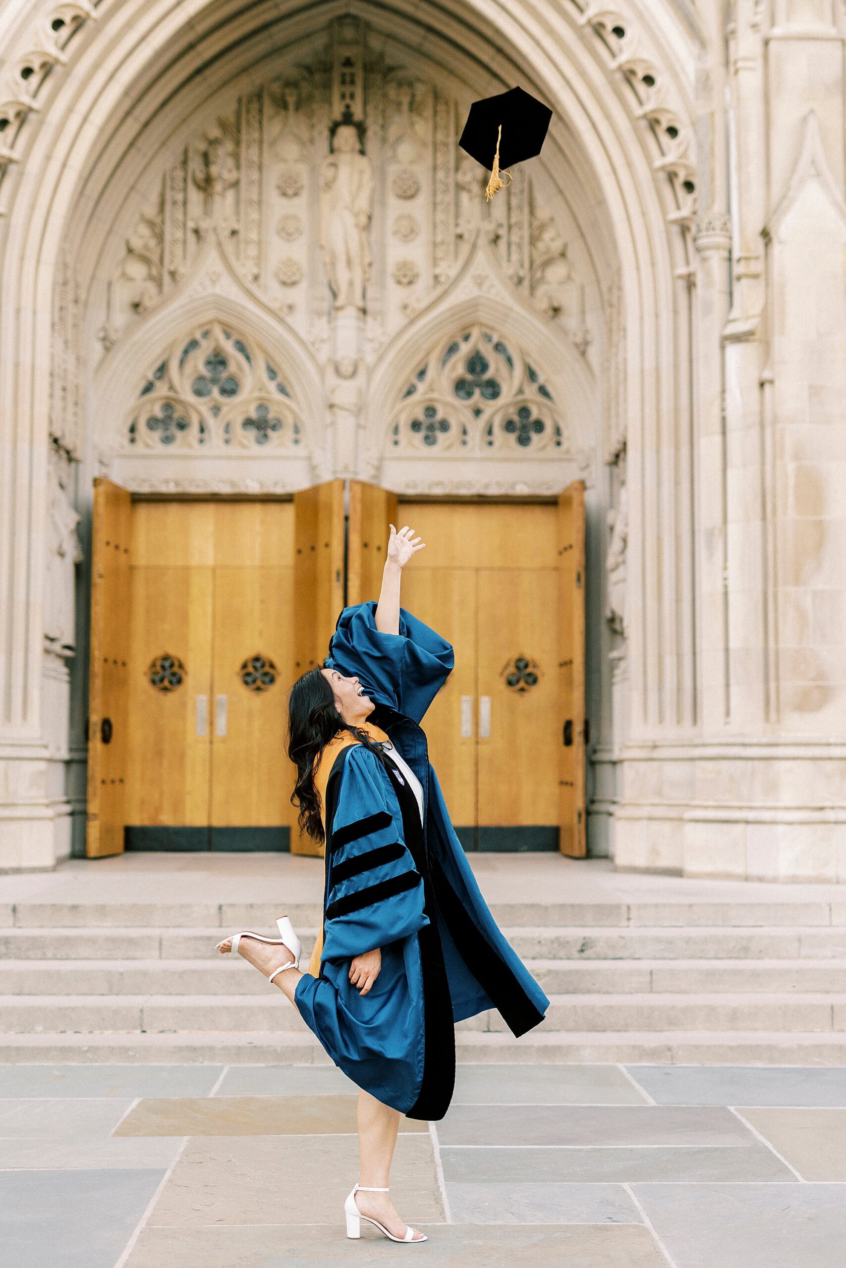 woman tosses hat in the air outside Duke University