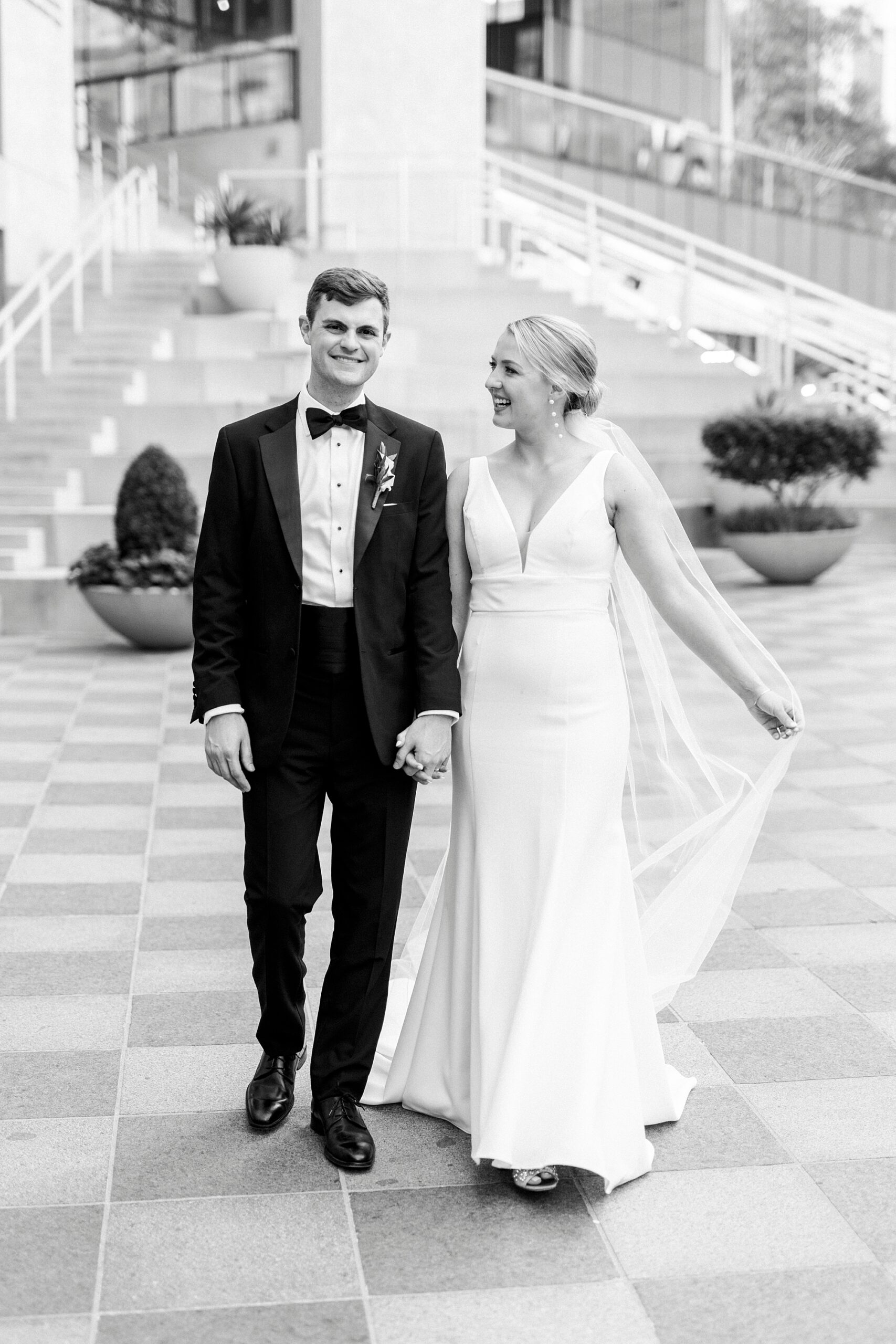 bride walks with groom across checkered floor at the Mint Museum Uptown