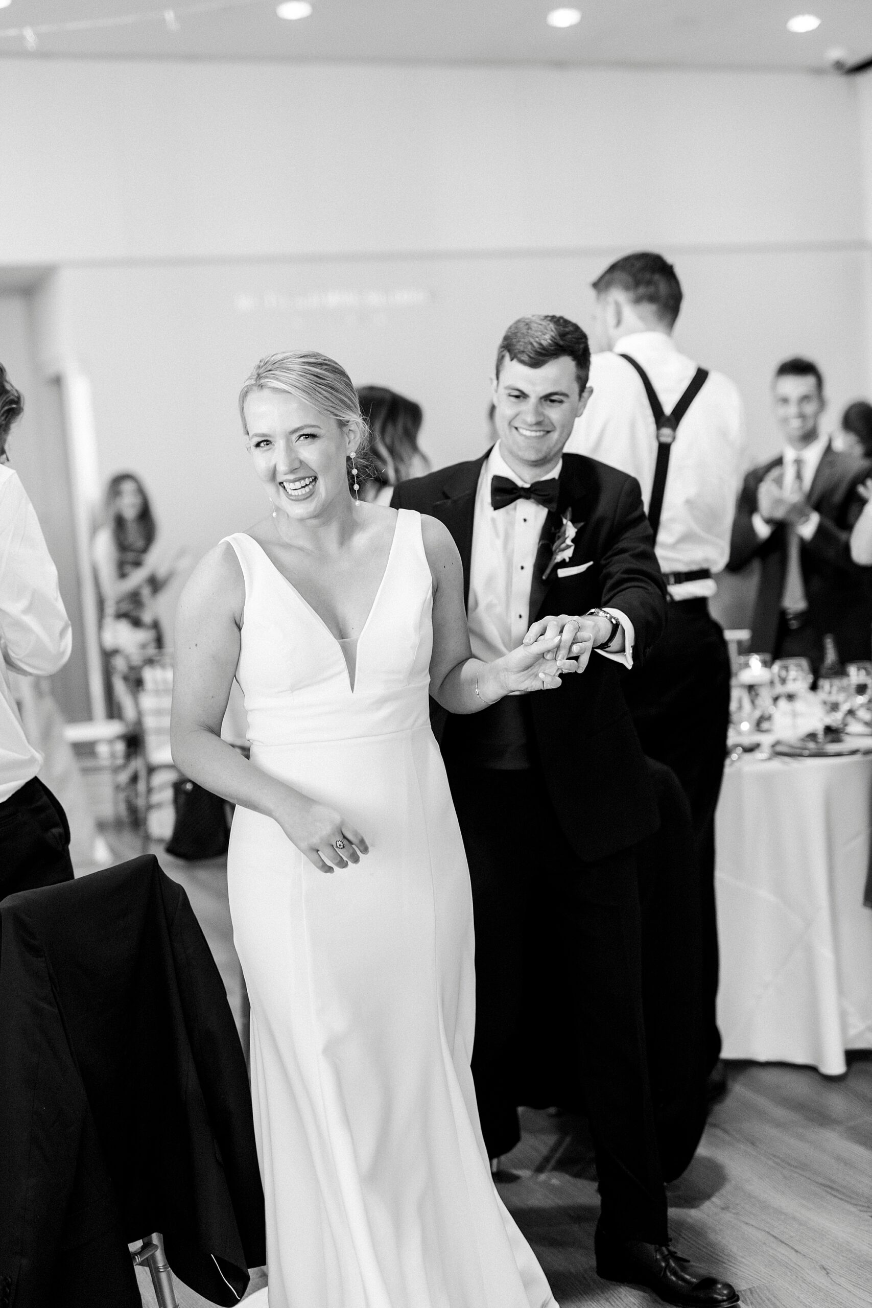 bride and groom enter reception at the Mint Museum Uptown with guests around them