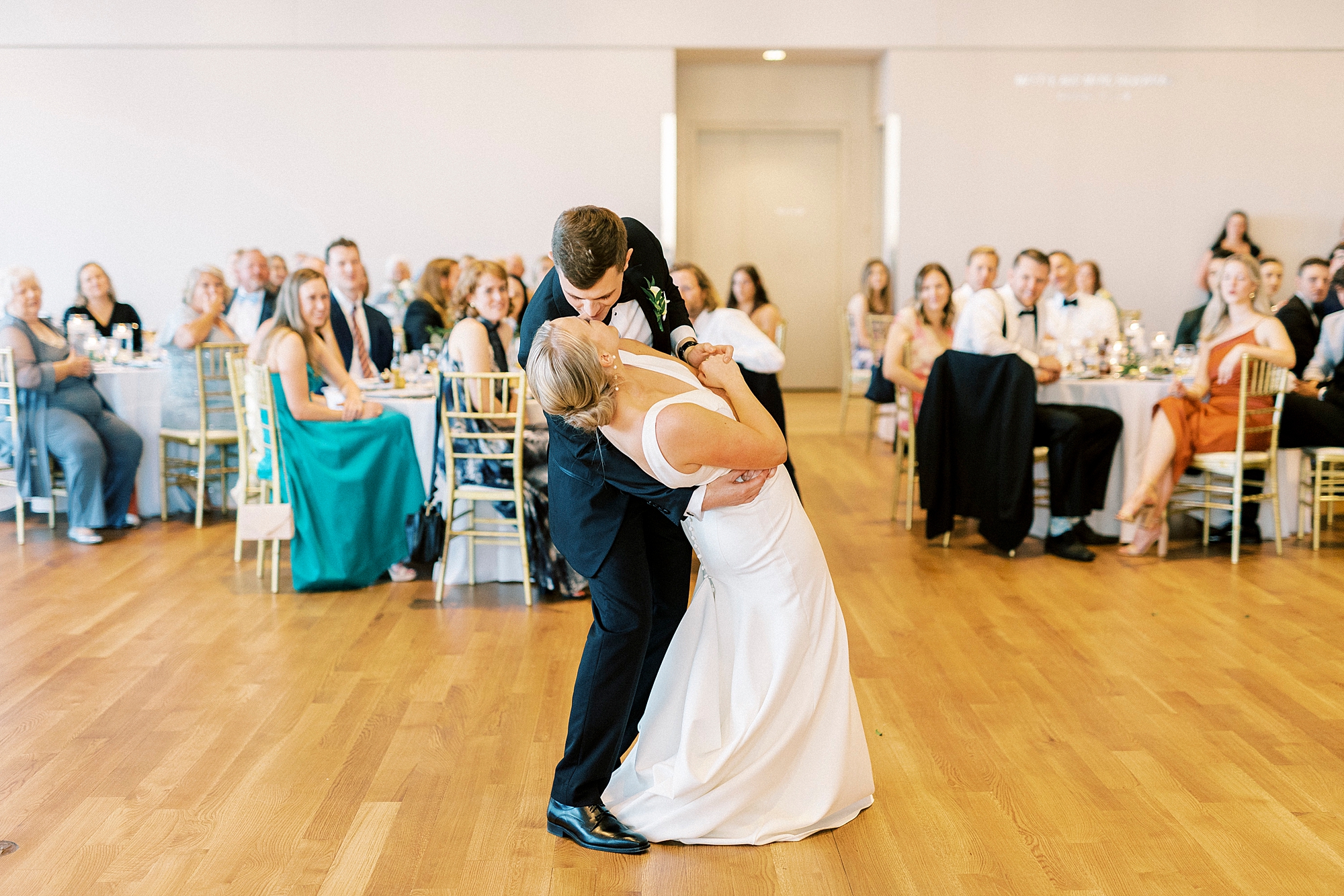 groom dips bride kissing her on dance floor at reception