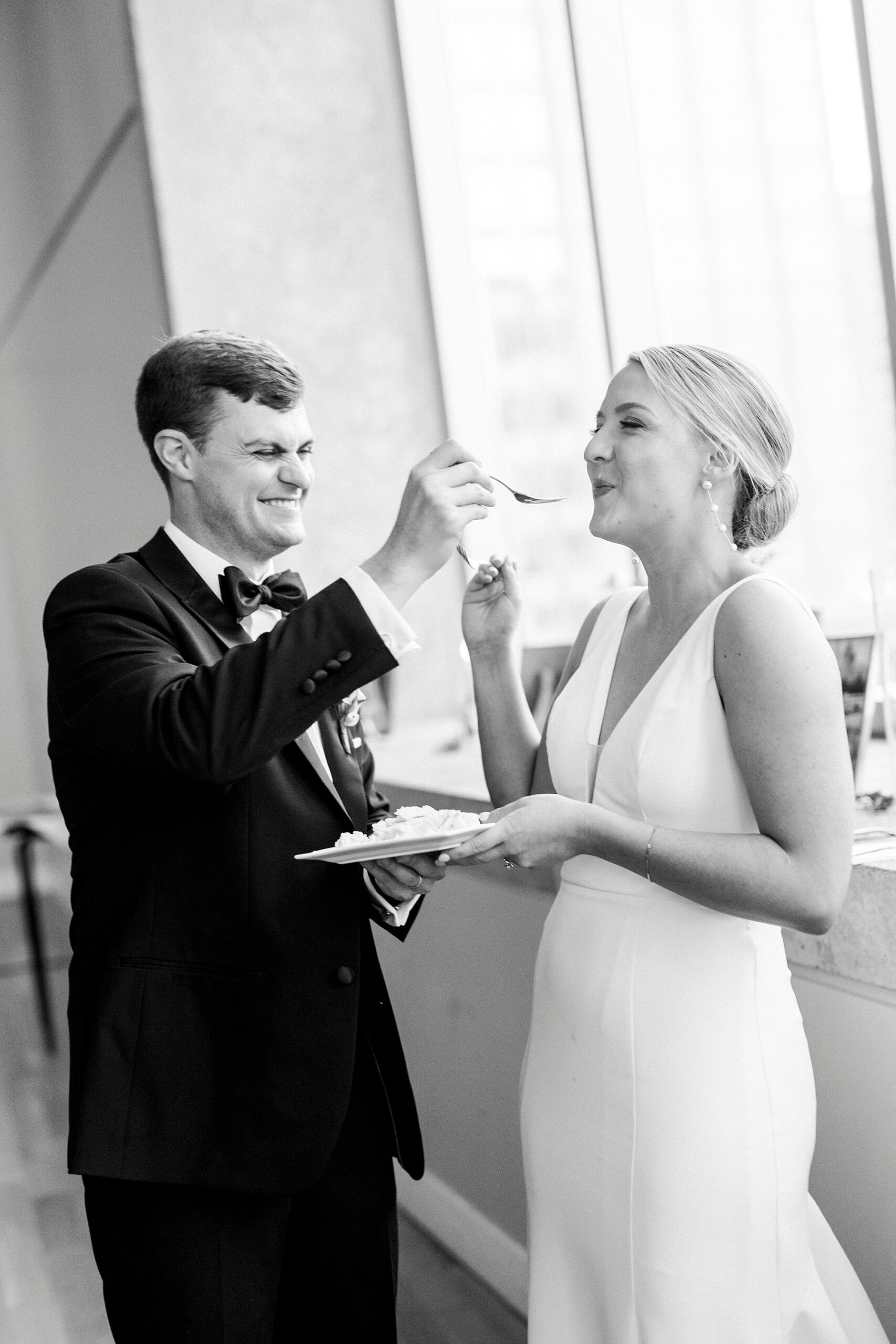 groom feeds bride cake during reception at the Mint Museum Uptown