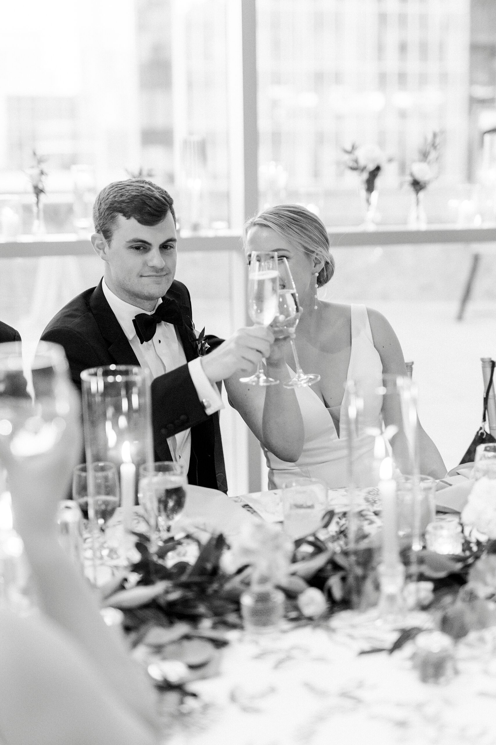groom lifts up champagne next to bride during reception at the Mint Museum Uptown