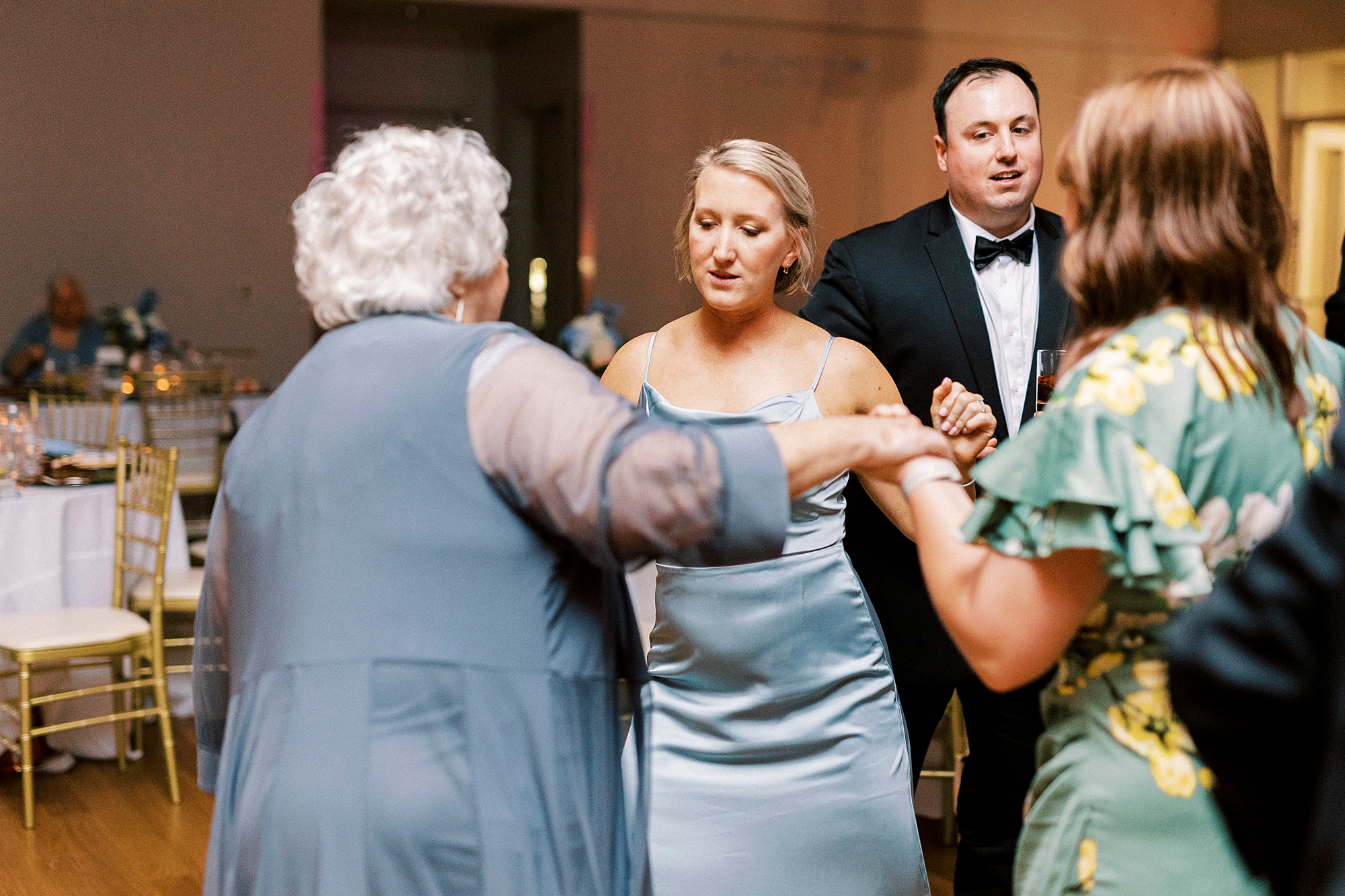 bridesmaid dances with older woman during reception at the Mint Museum Uptown
