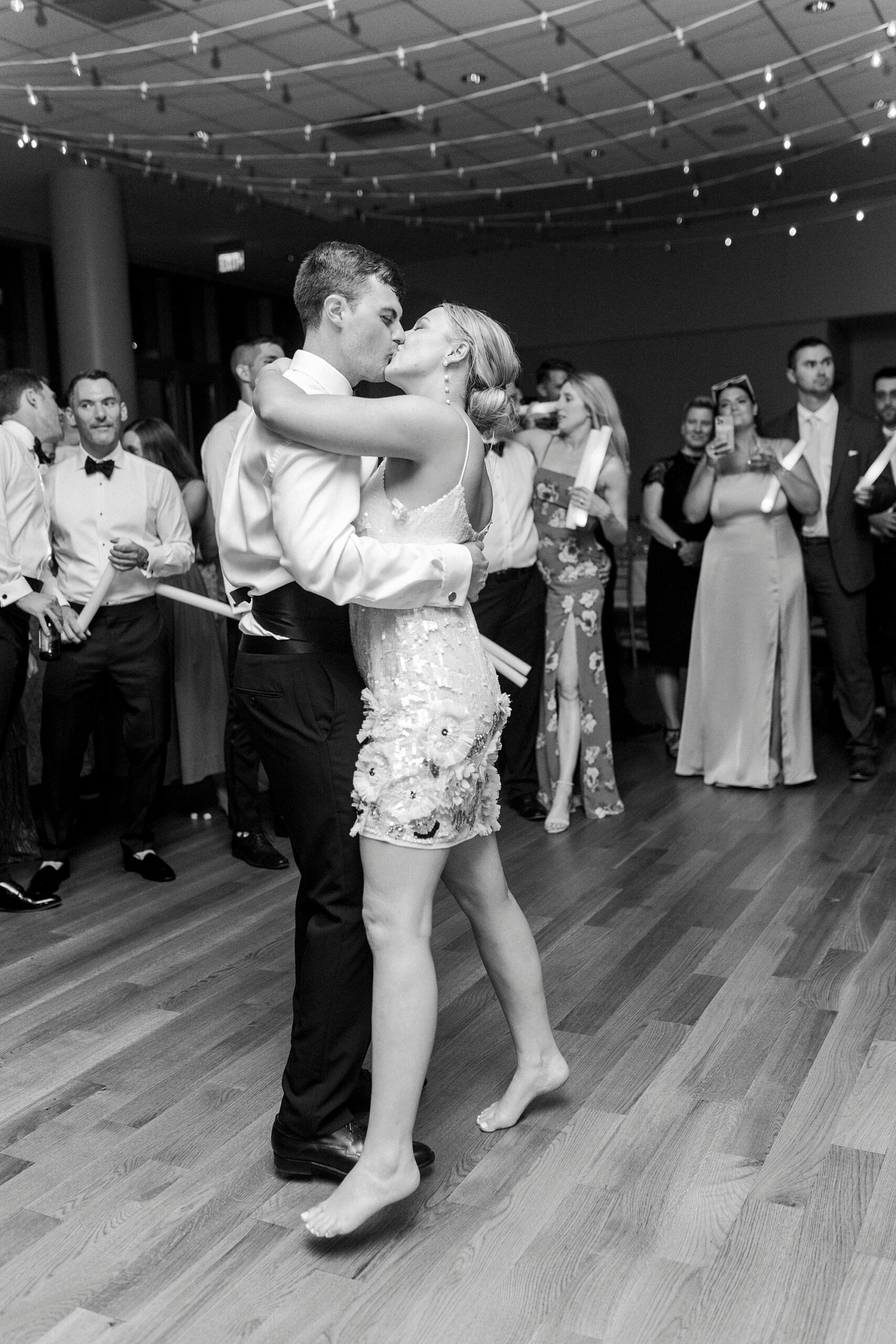 bride in short white party dress kisses groom on dance floor