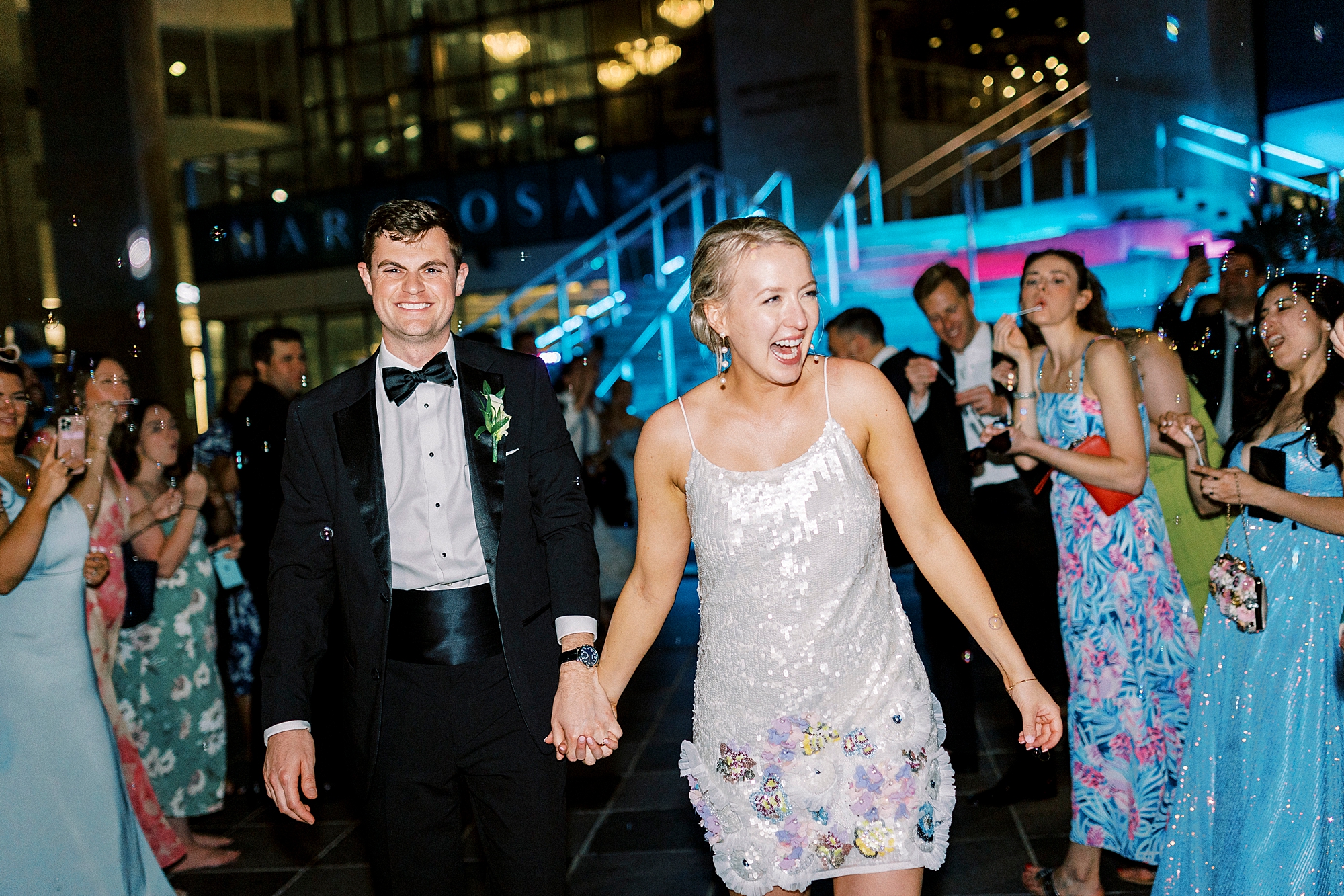 bride grins holding grooms hand leaving line of guests at the Mint Museum Uptown