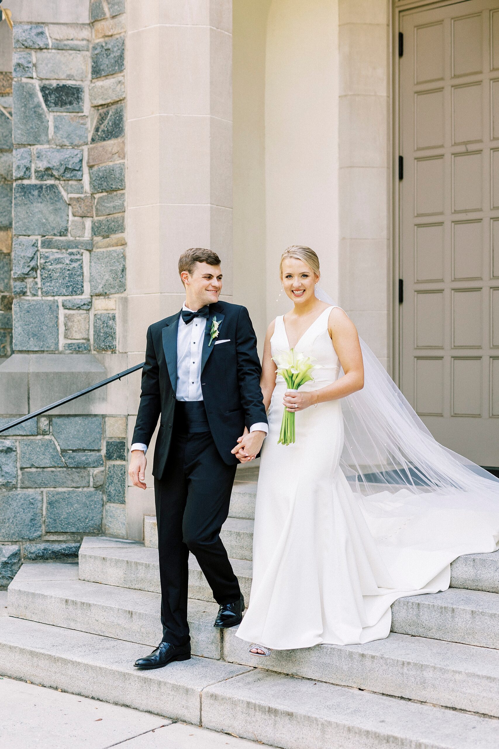 groom helps bride down steps of church in Charlotte NC