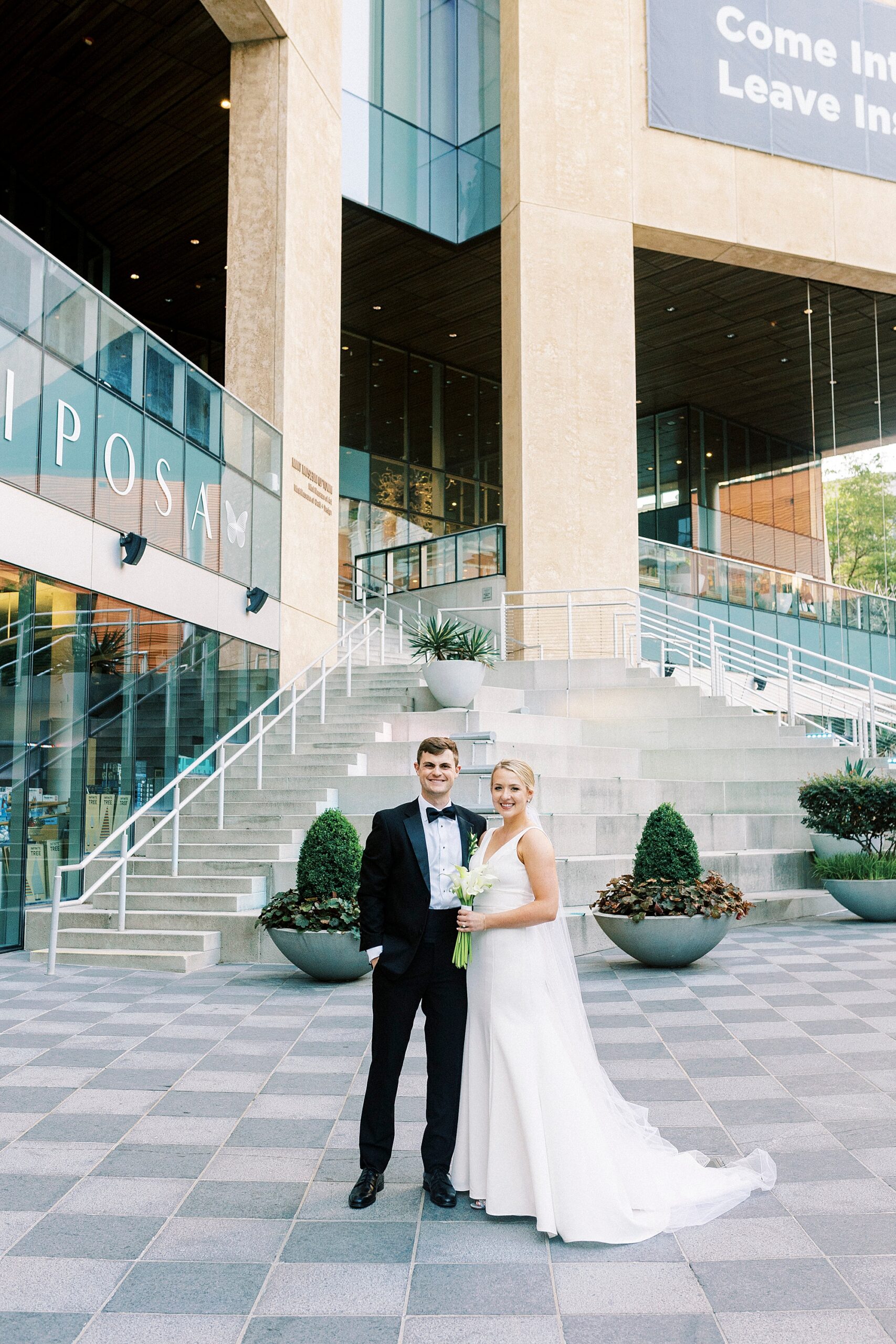 newlyweds pose hugging on patio of the Mint Museum Uptown