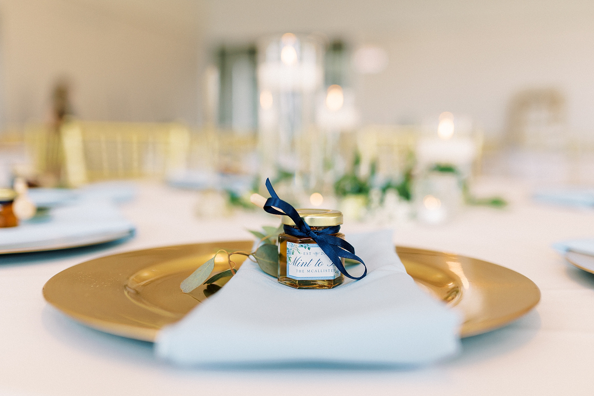 place setting for summer wedding at the Mint Museum Uptown with gold plates and blue napkins