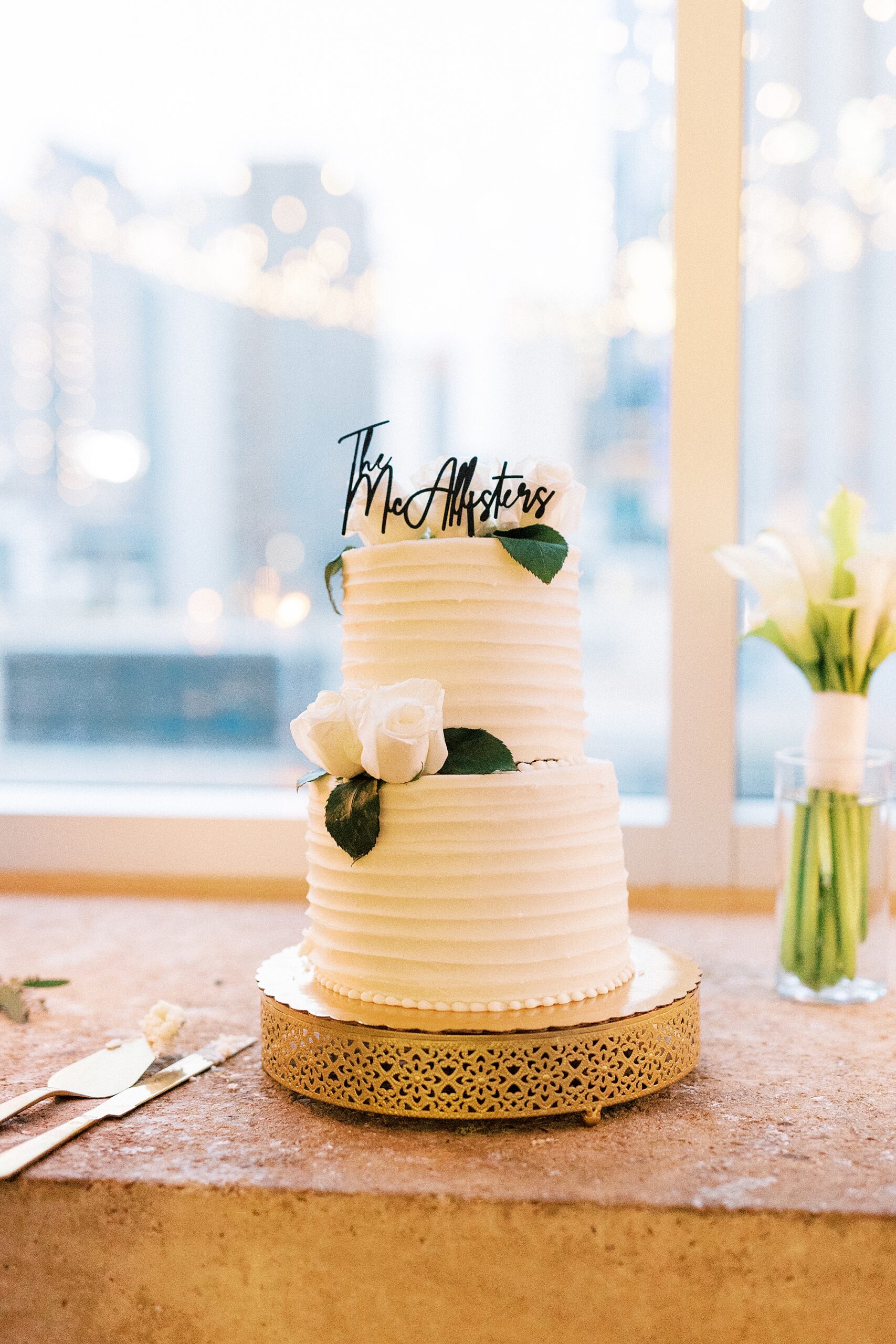 tiered wedding cake with topper and white roses