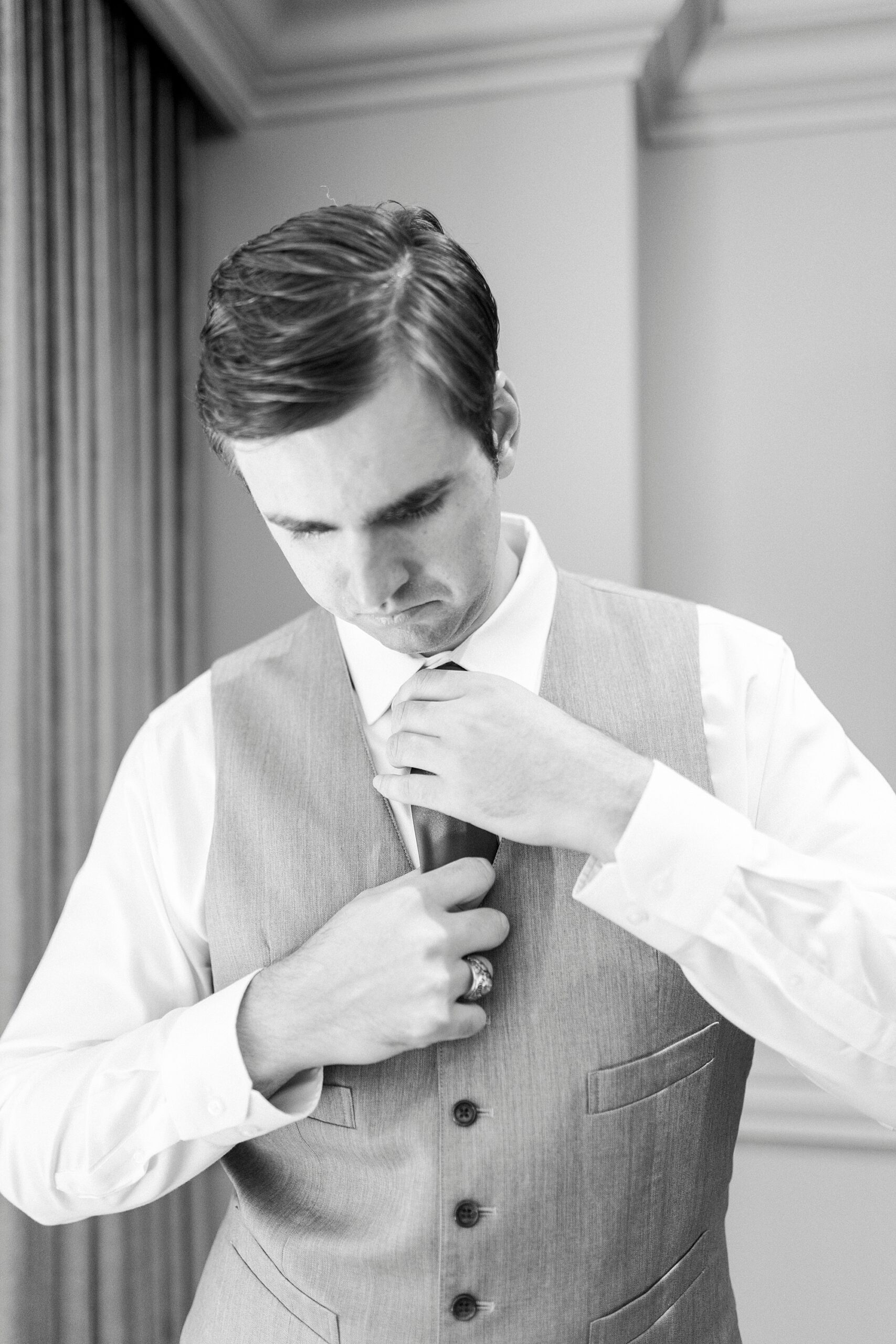 groom adjusts tie while preparing for NC wedding