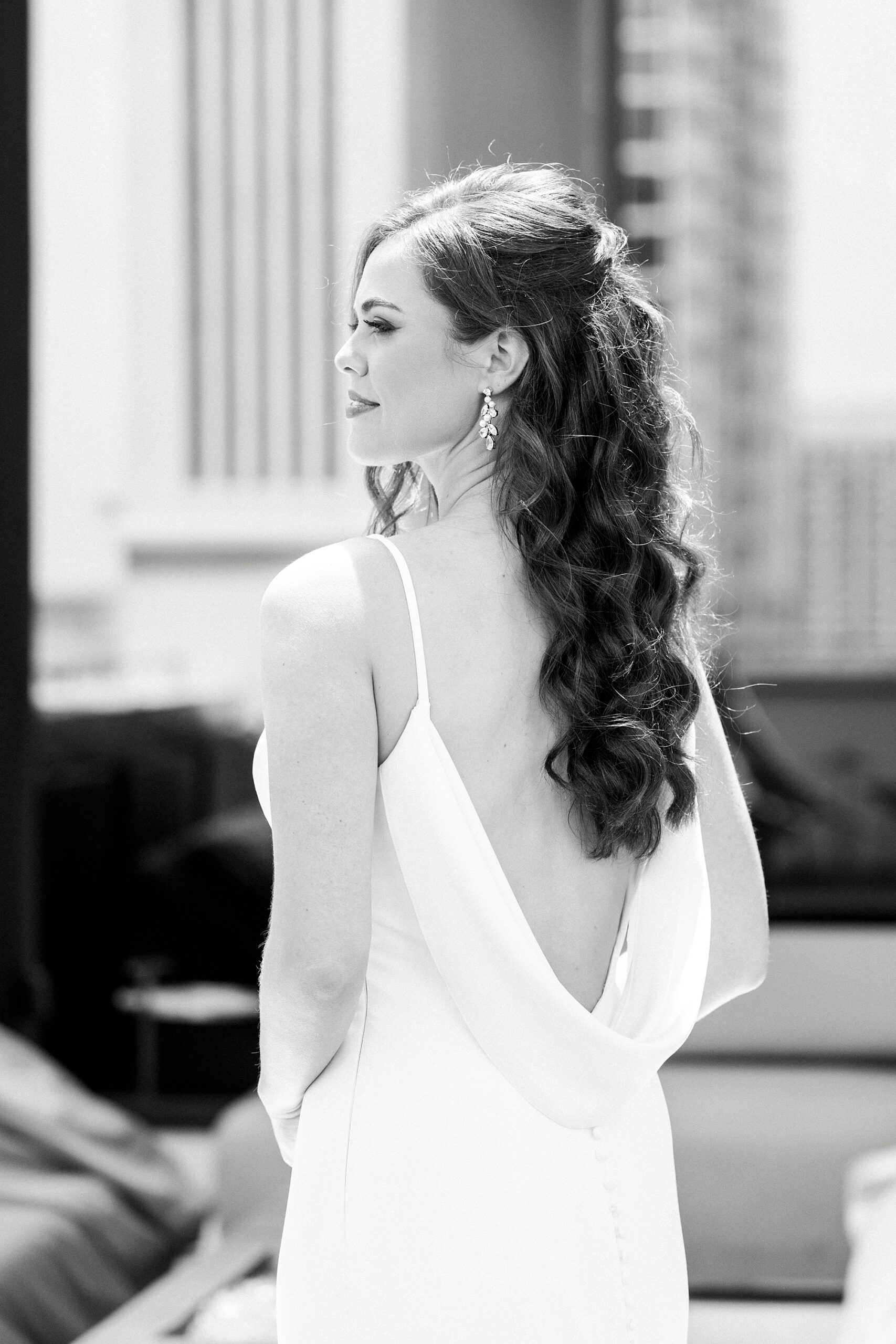 bride smiles over shoulder showing off back of dress