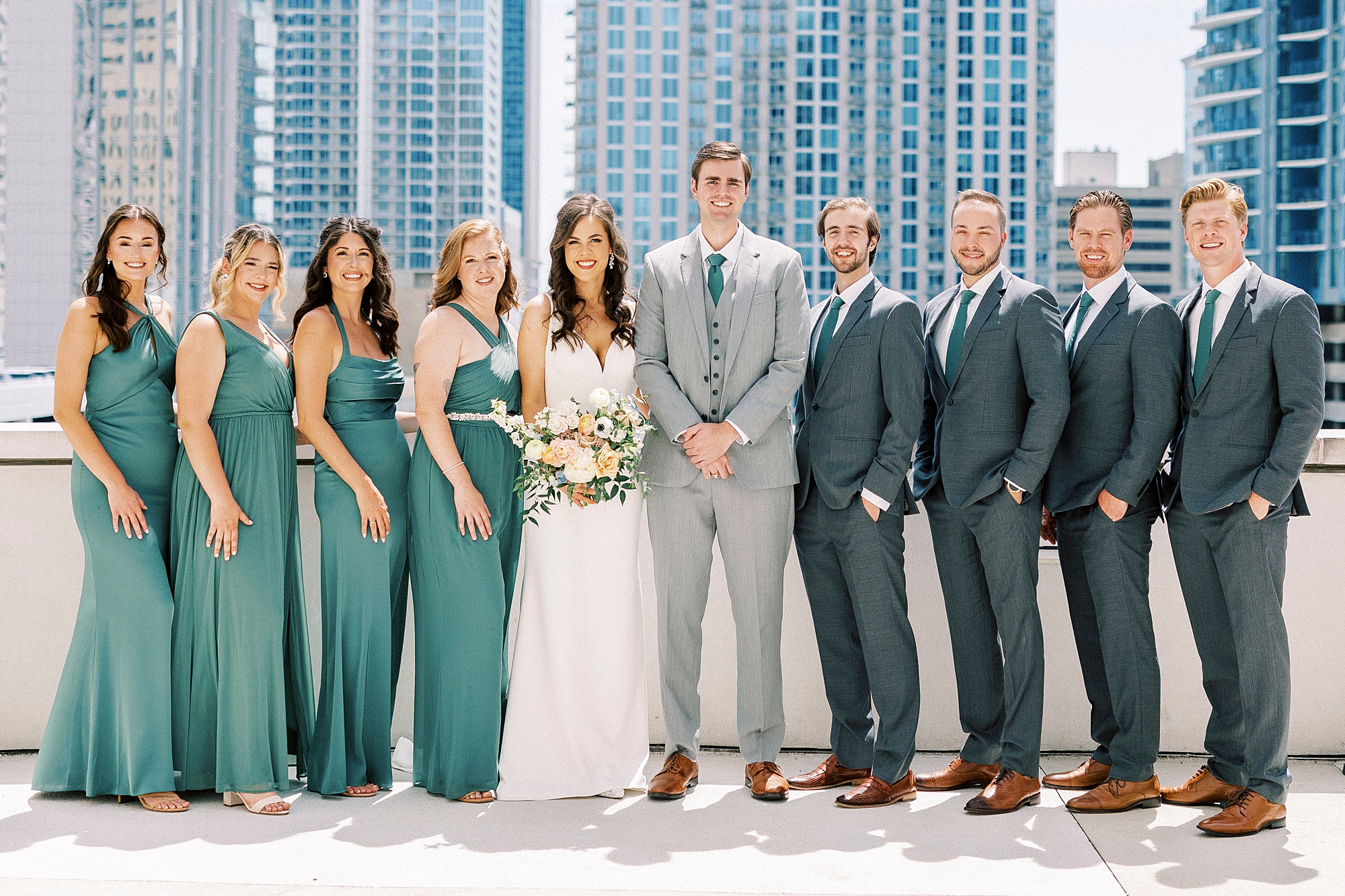 bride and groom pose with wedding party on rooftop of Charlotte hotel