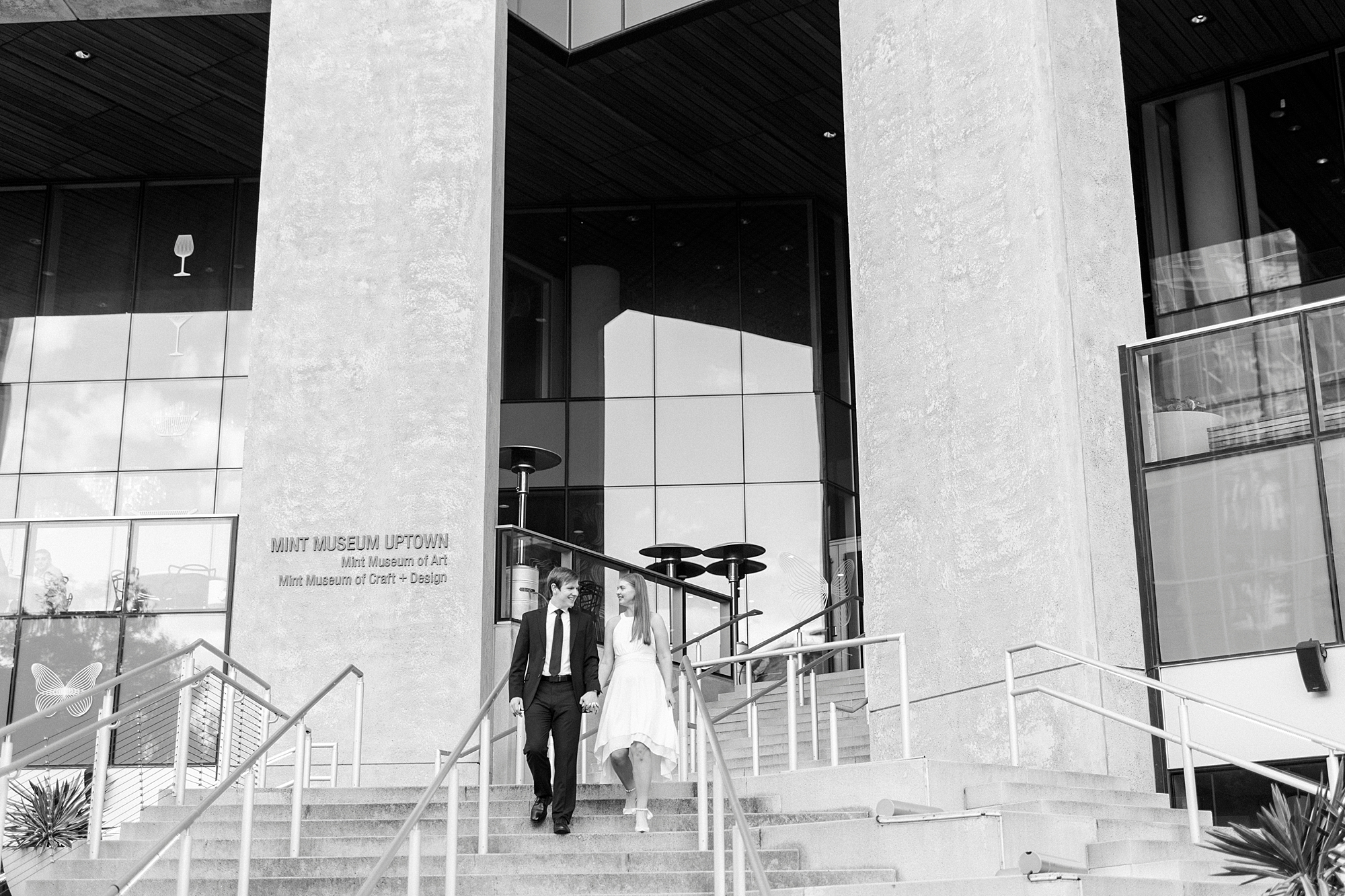 engaged couple holds hands walking down steps of the Mint Museum in Charlotte NC