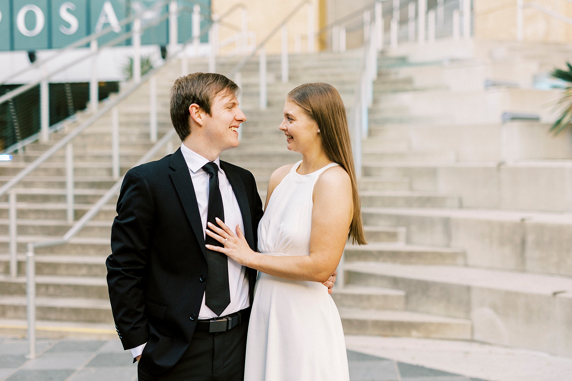 woman in white dress smiles at man in black suit in Charlotte NC