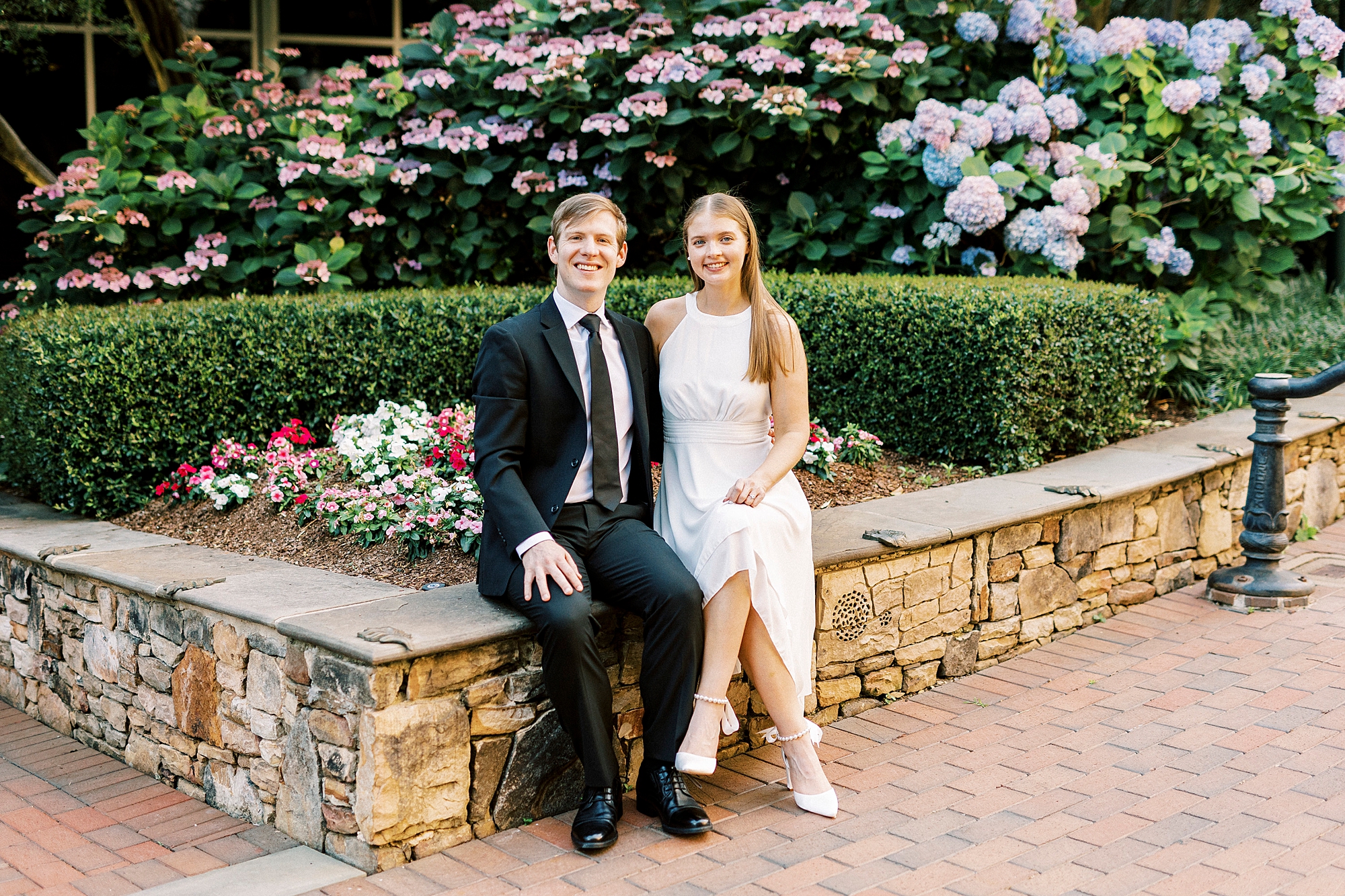 man and woman sit on stone bench in Charlotte NC park