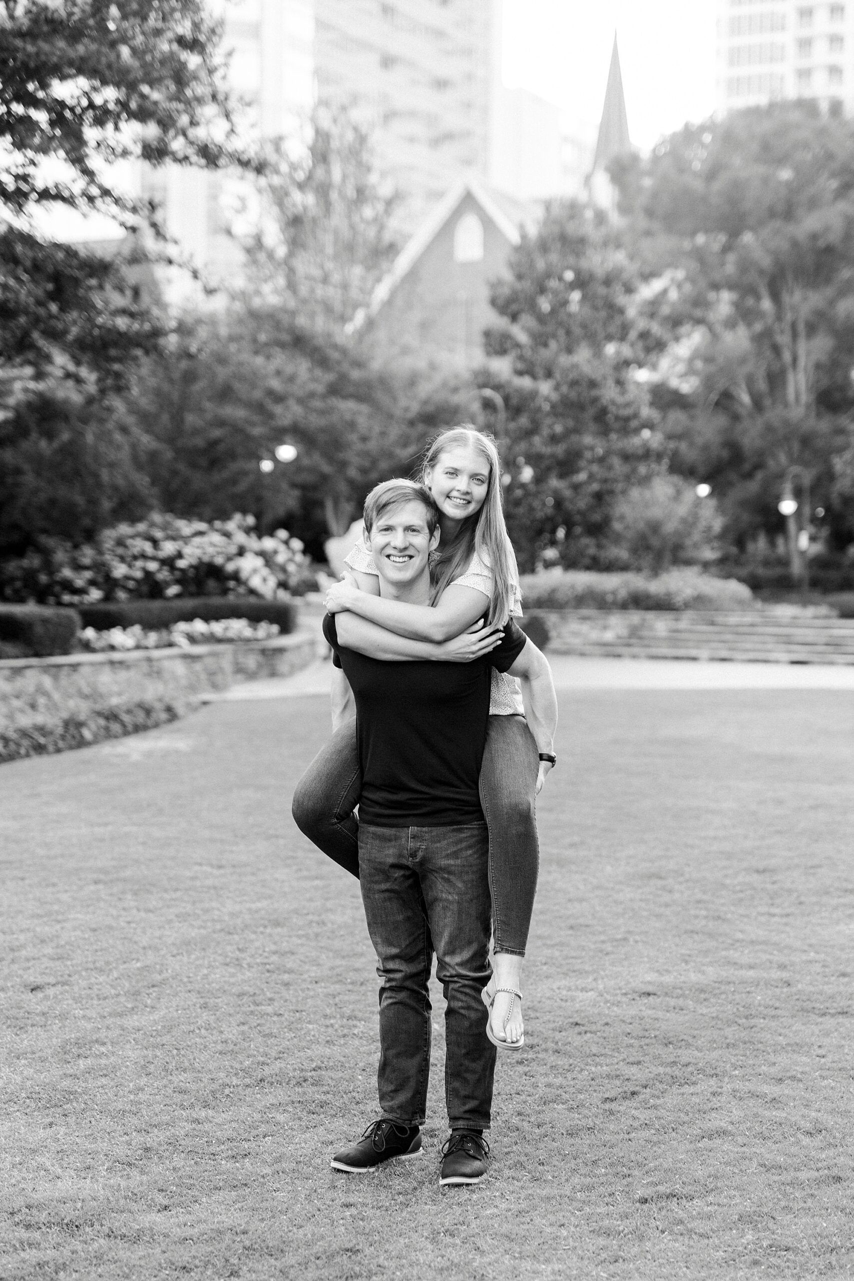 man gives woman a piggy back ride with Charlotte skyline behind them