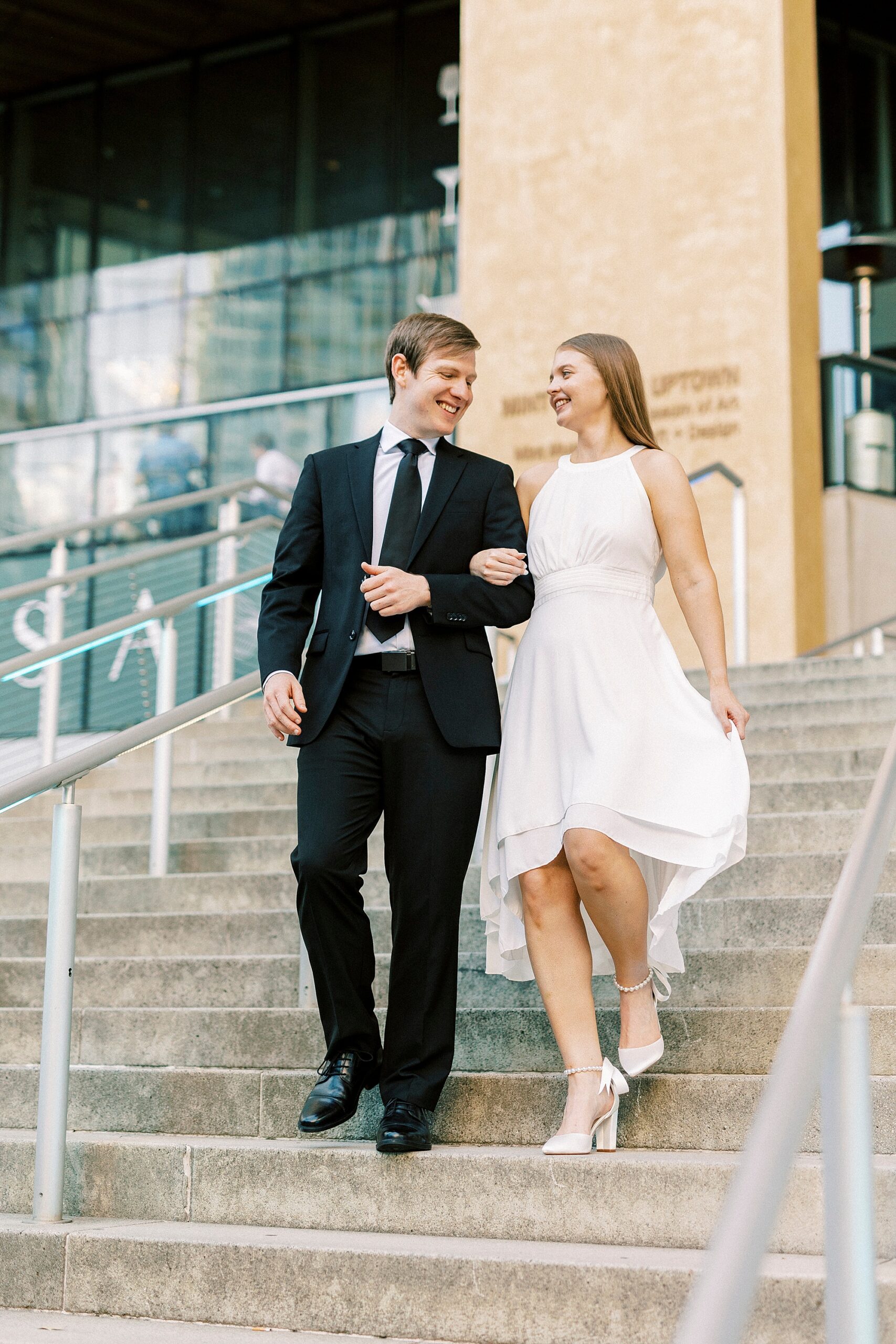 engaged couple walks down steps inside the Mint Museum in Charlotte NC