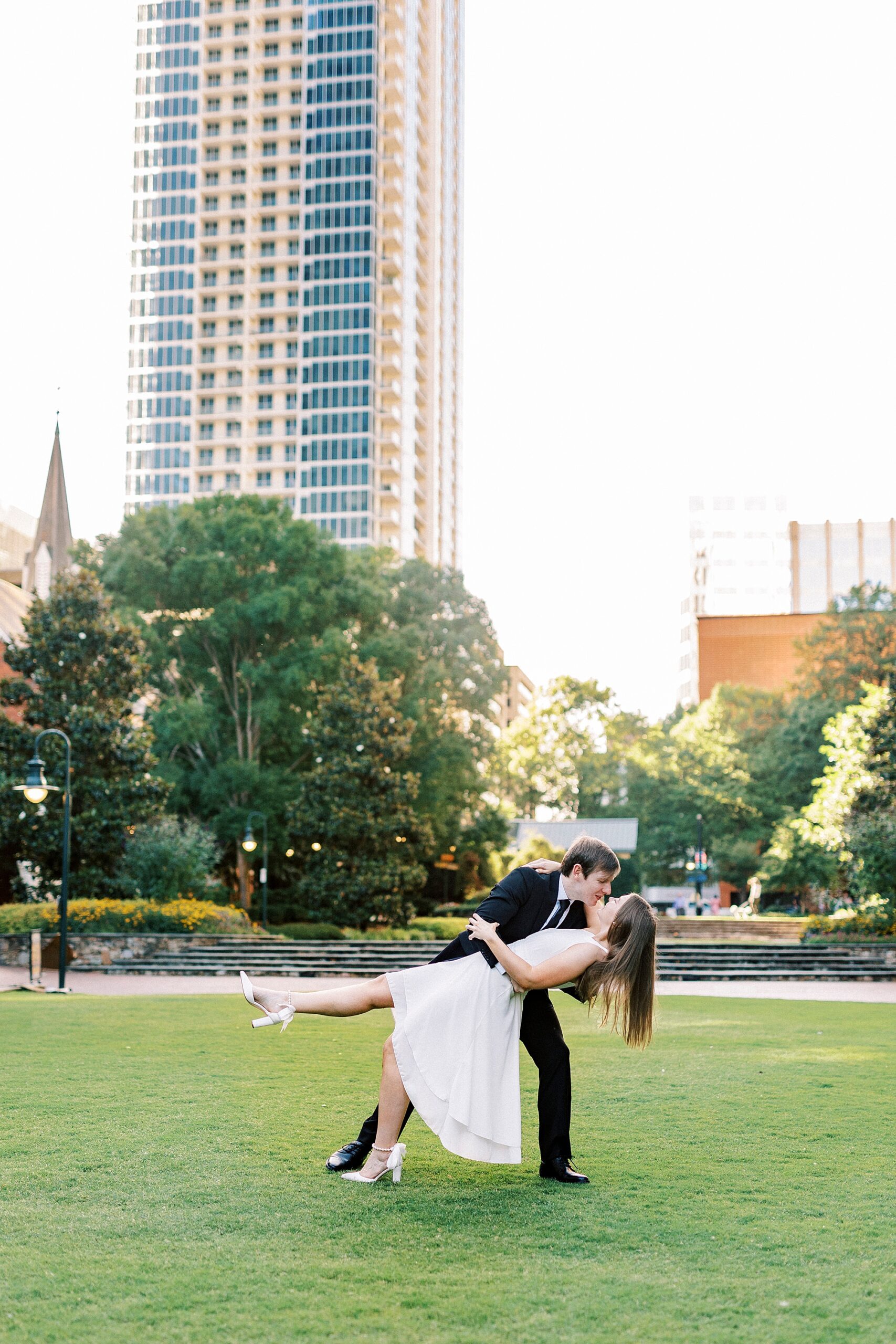 man dips woman kissing her at sunset on Charlotte green