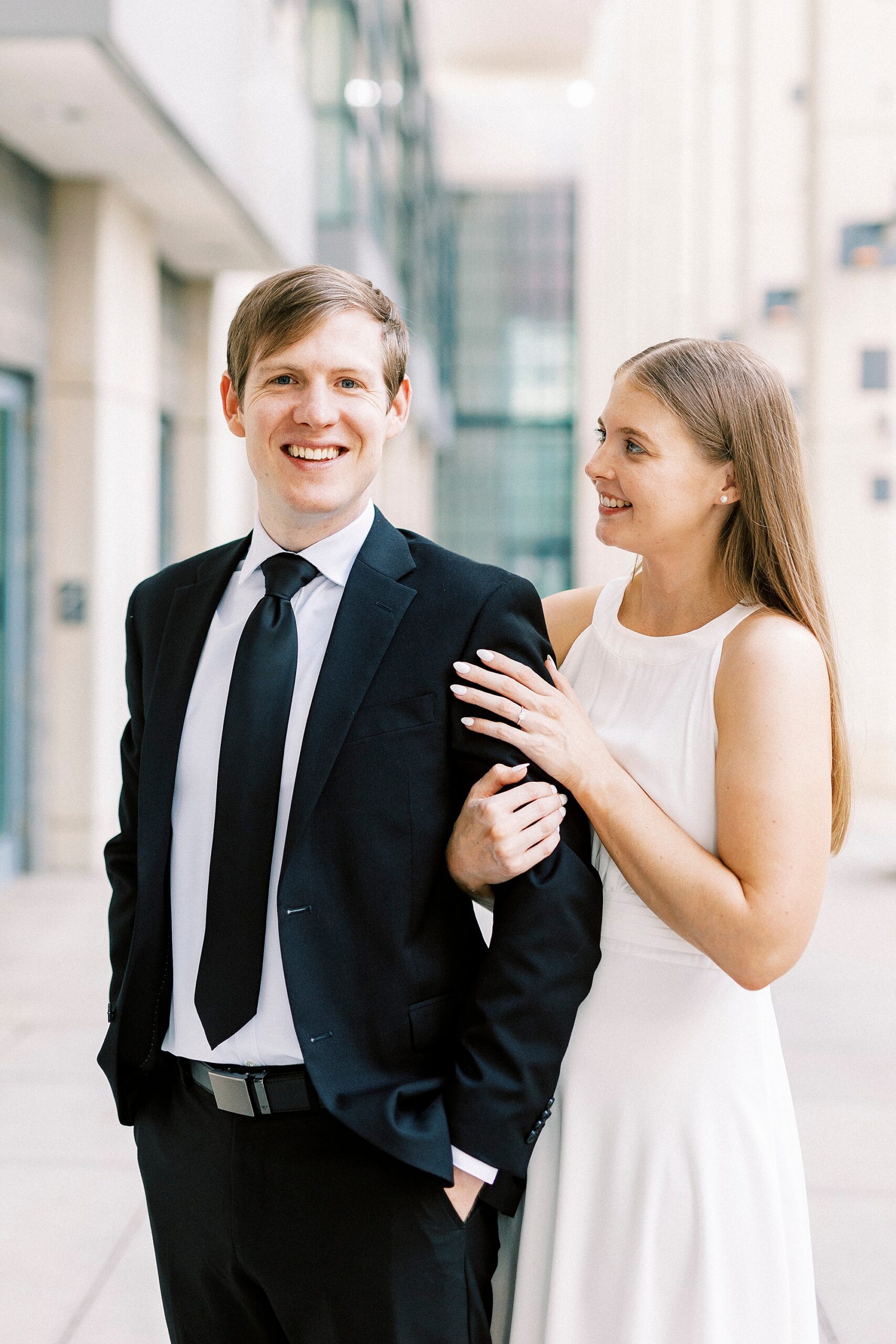 woman in white dress holds man's arm smiling at him at Charlotte Convention Center 