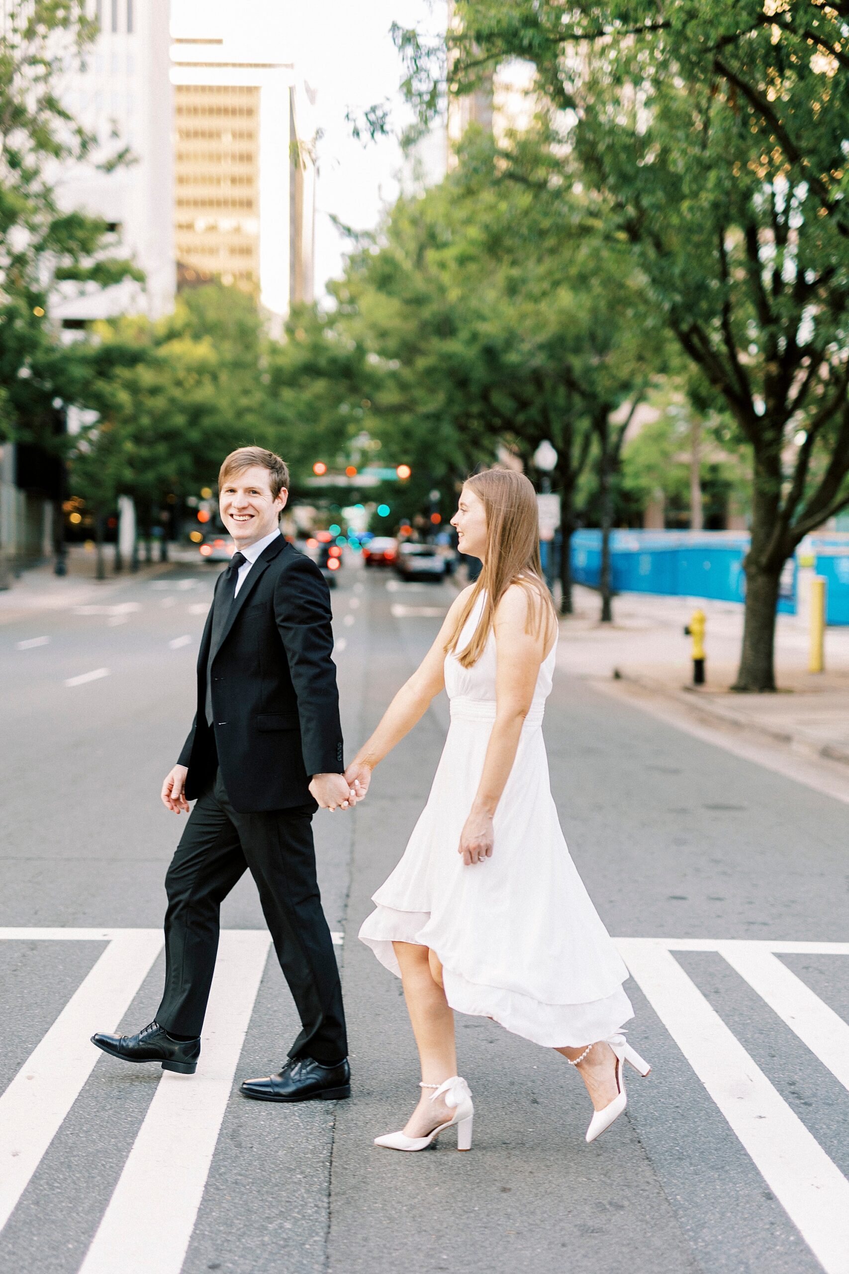 man holds woman's hand as they cross street in Uptown Charlotte NC