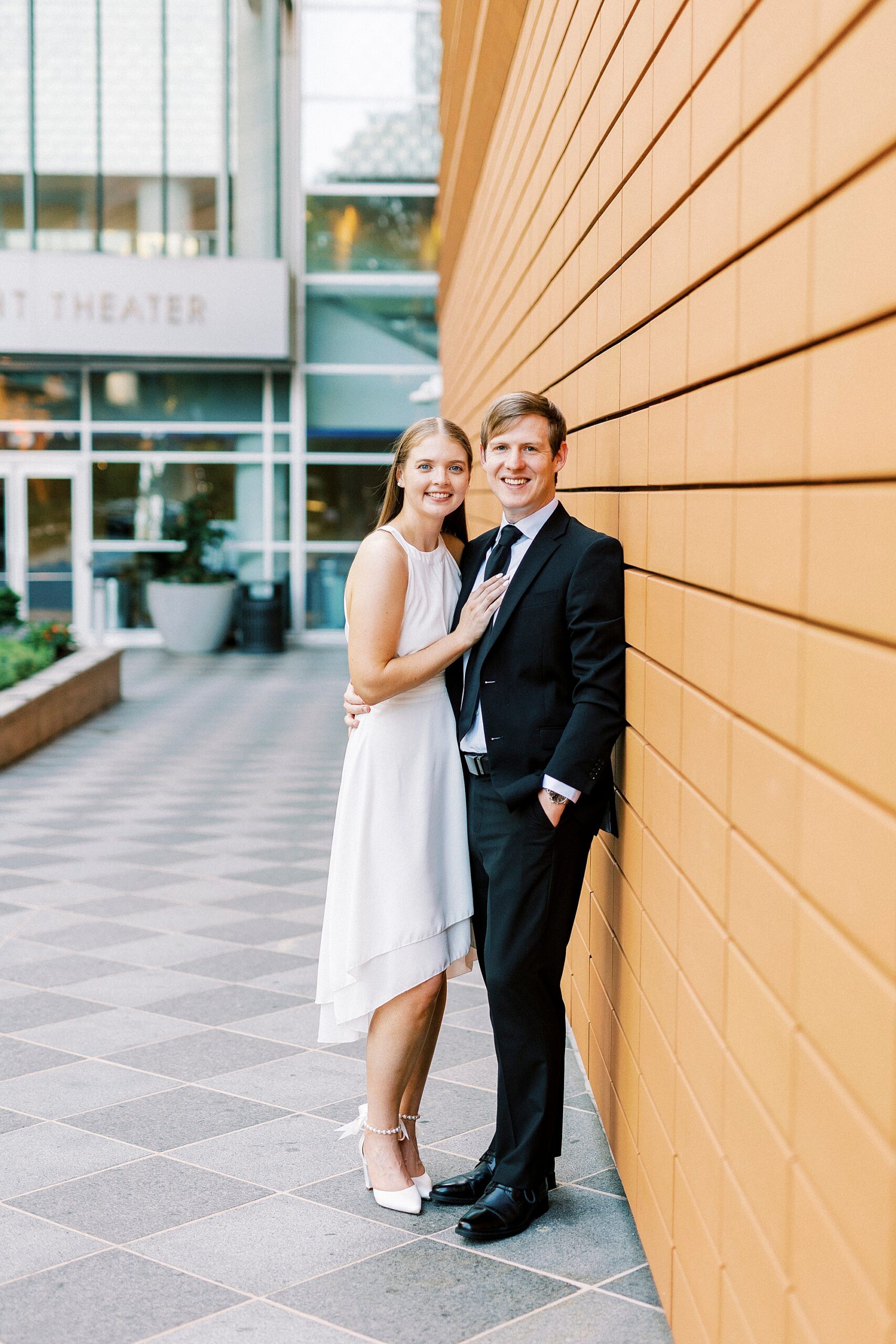 woman leans into man against orange wall of Mint Museum 