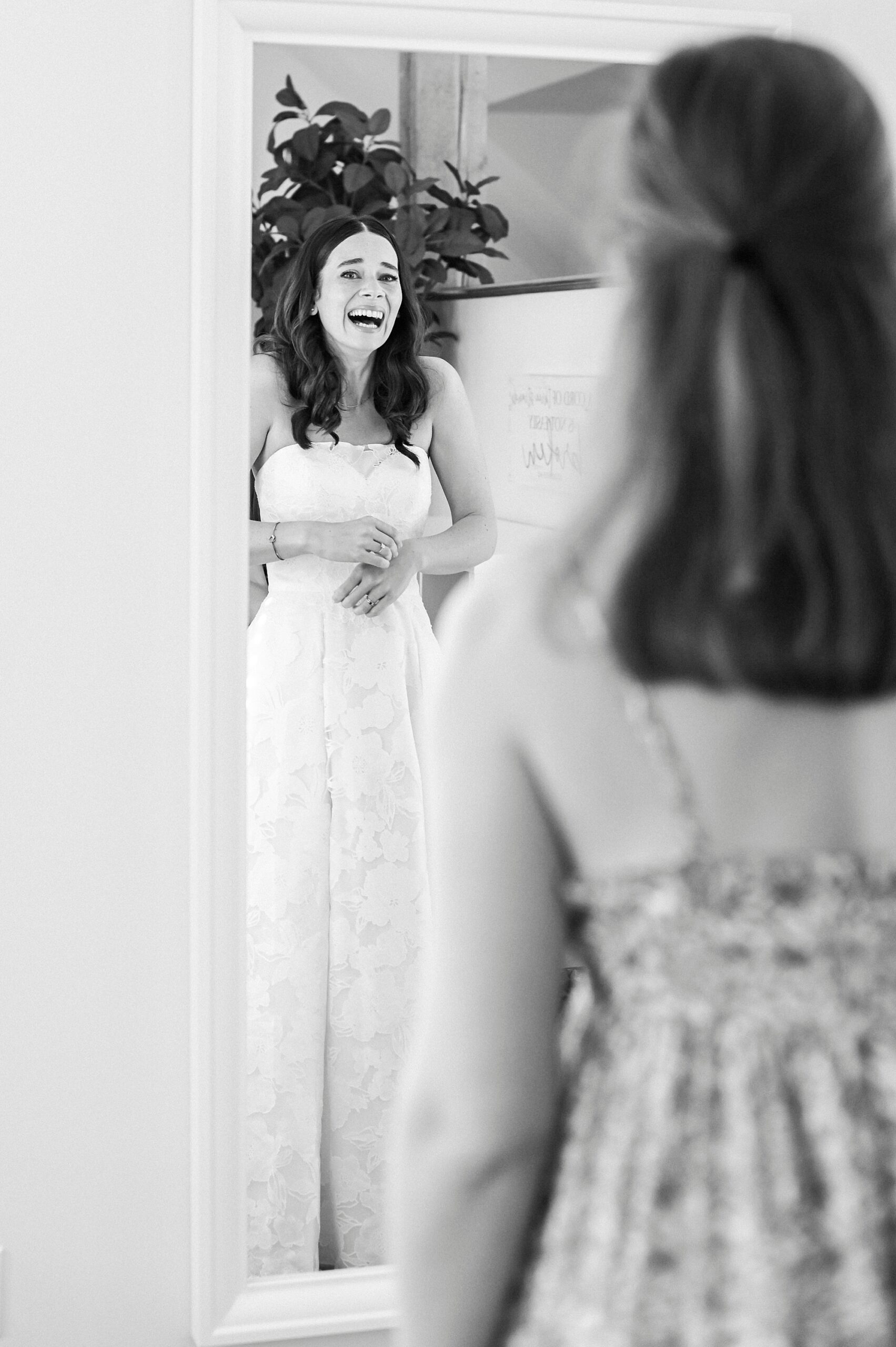bride laughs looking in mirror wearing wedding dress