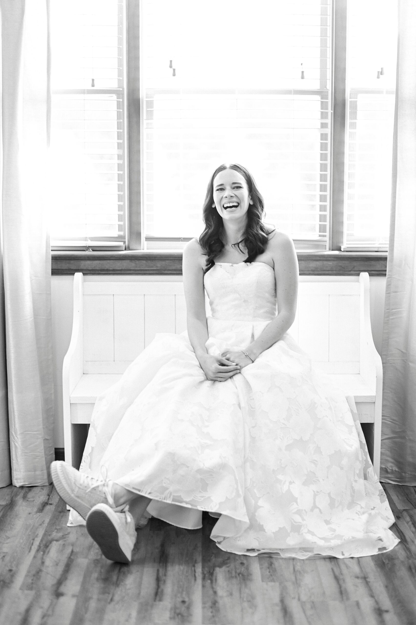 black and white photo of bride laughing sitting in wedding dress
