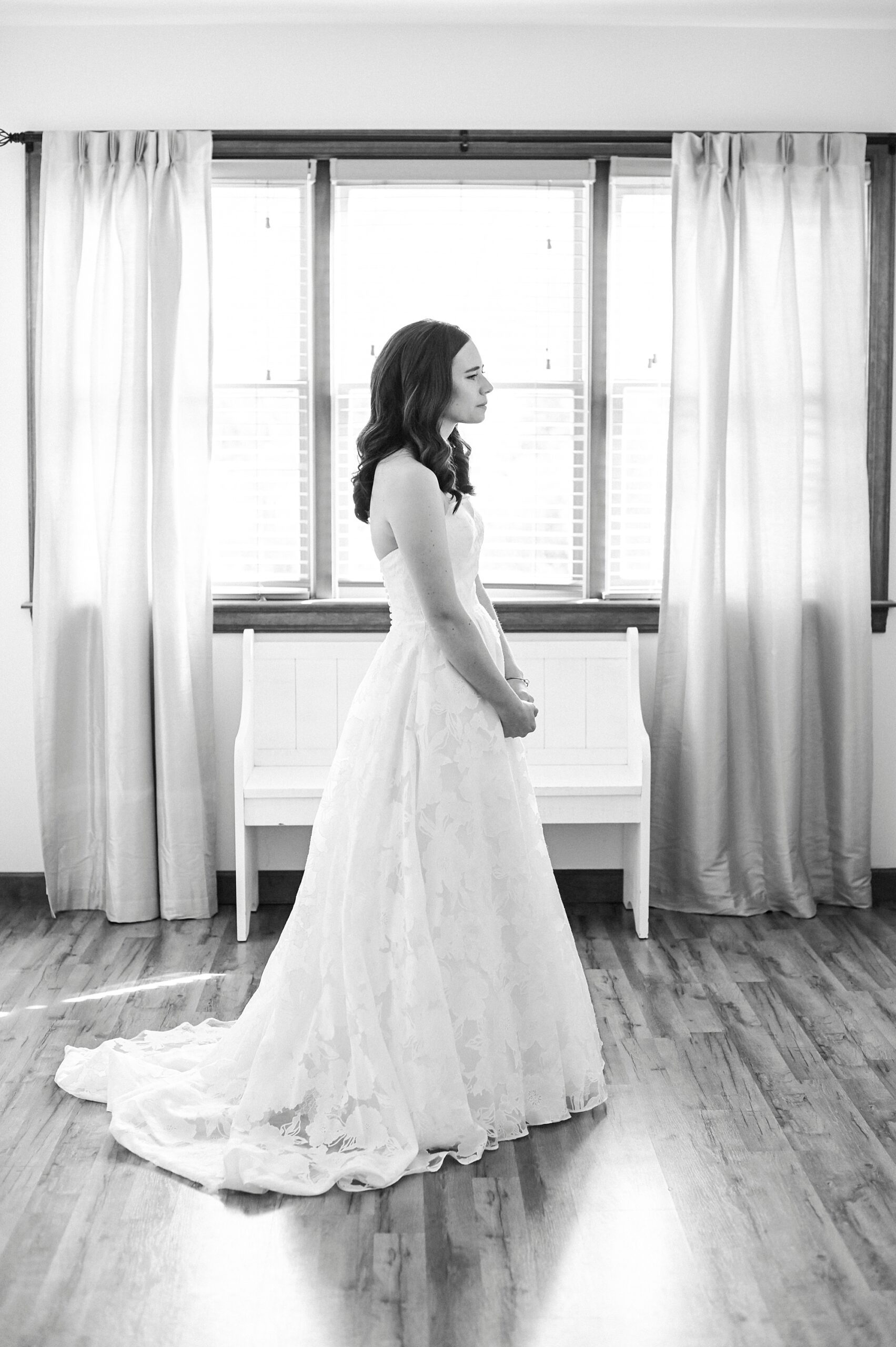 black and white photo of bride standing in strapless wedding gown