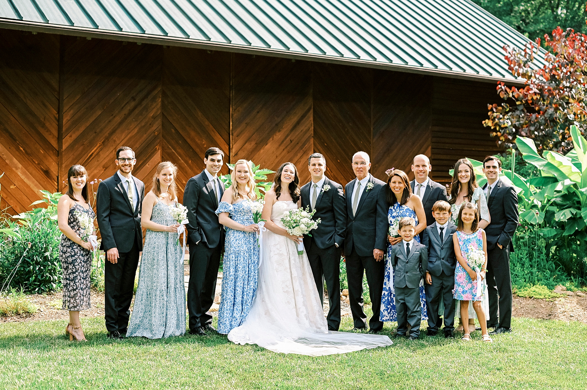 newlyweds pose with family outside barn at Alexander Homestead