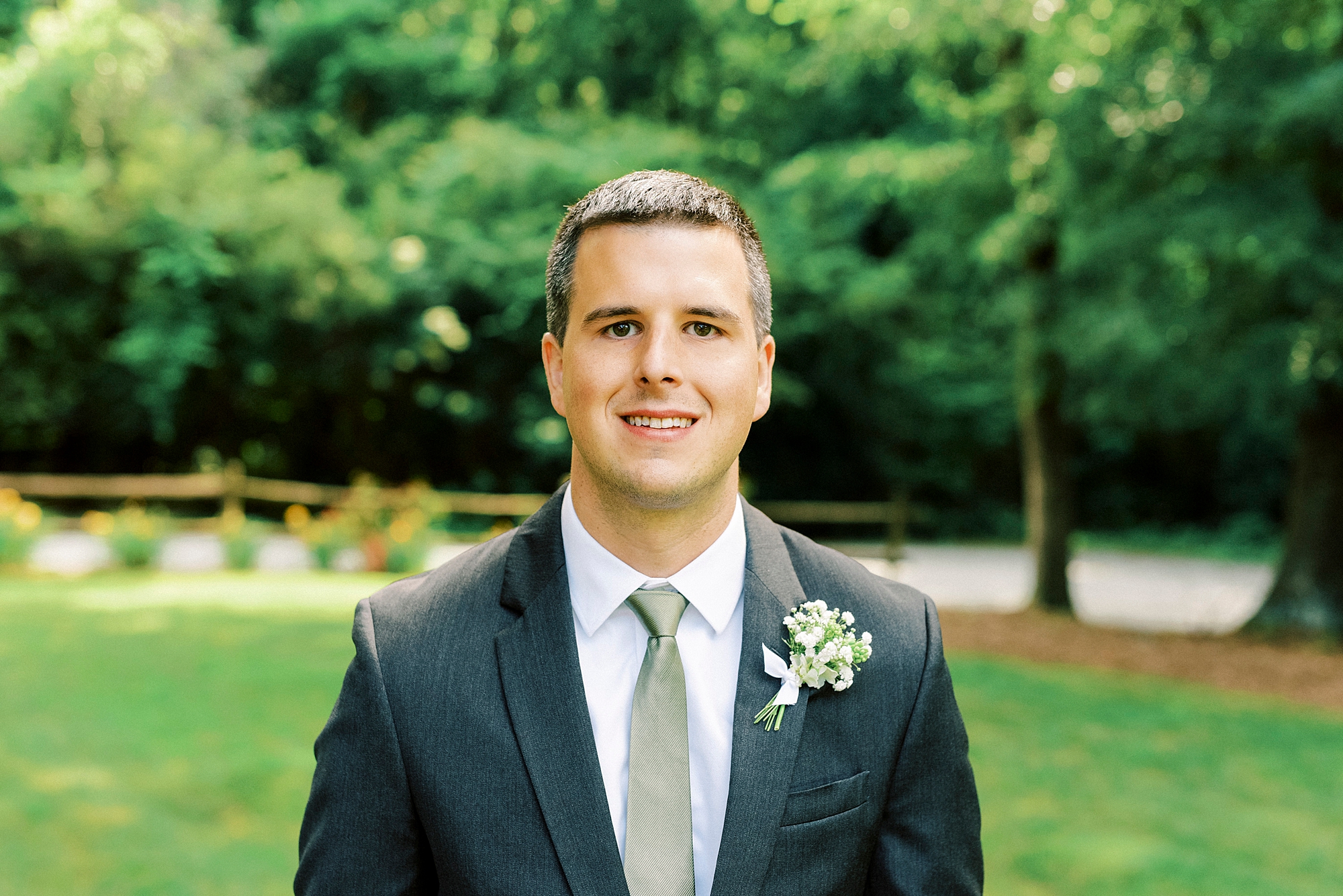 groom smiles in blue suit with white boutonnière
