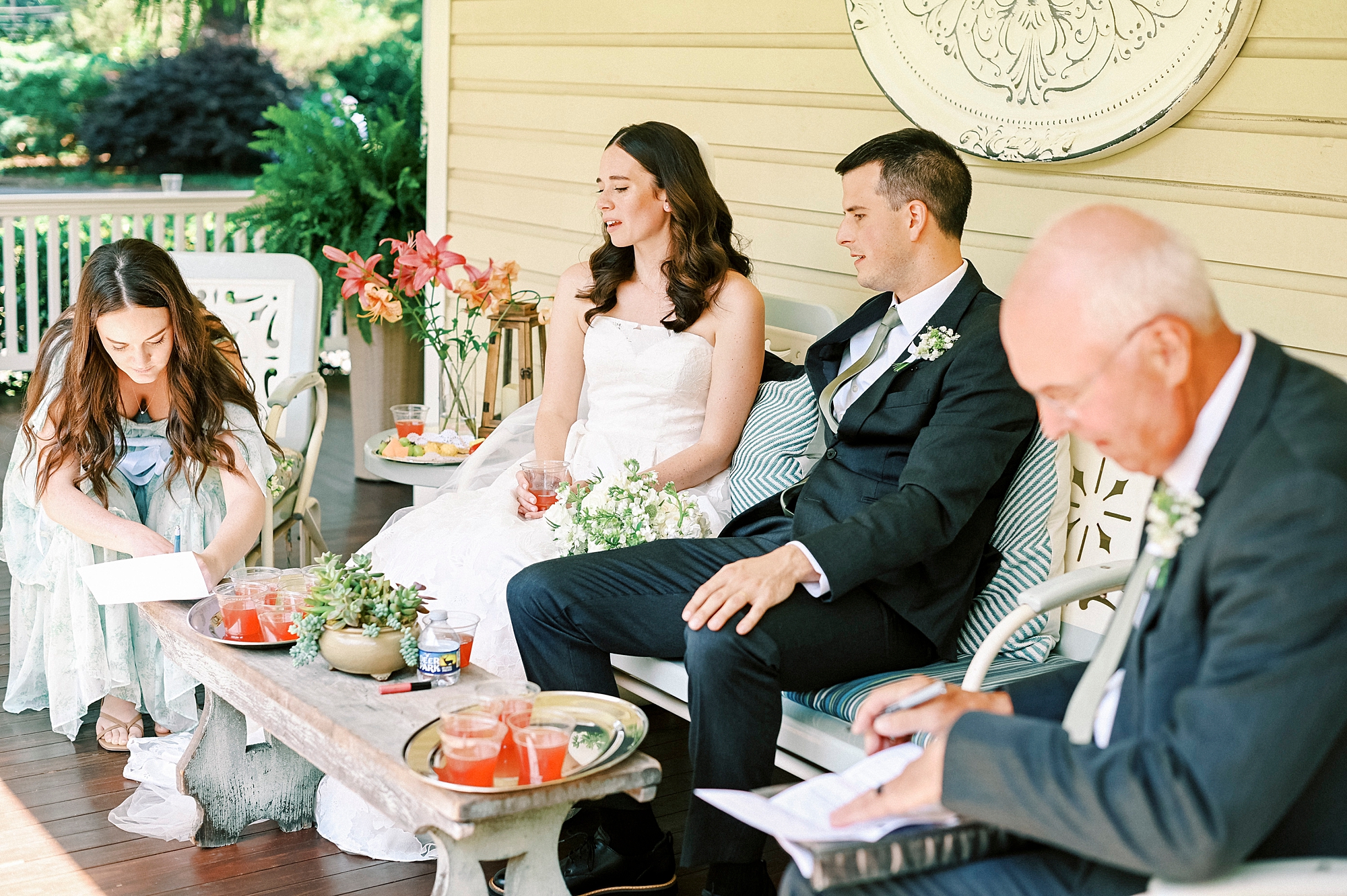 bride and groom sit on porch with family at Alexander Homestead