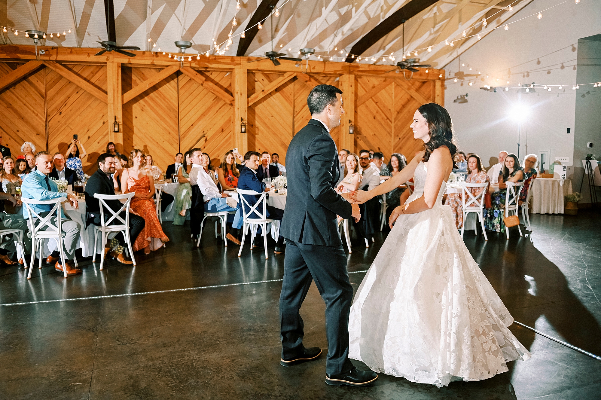 groom twirls bride on dance floor in barn at Alexander Homestead