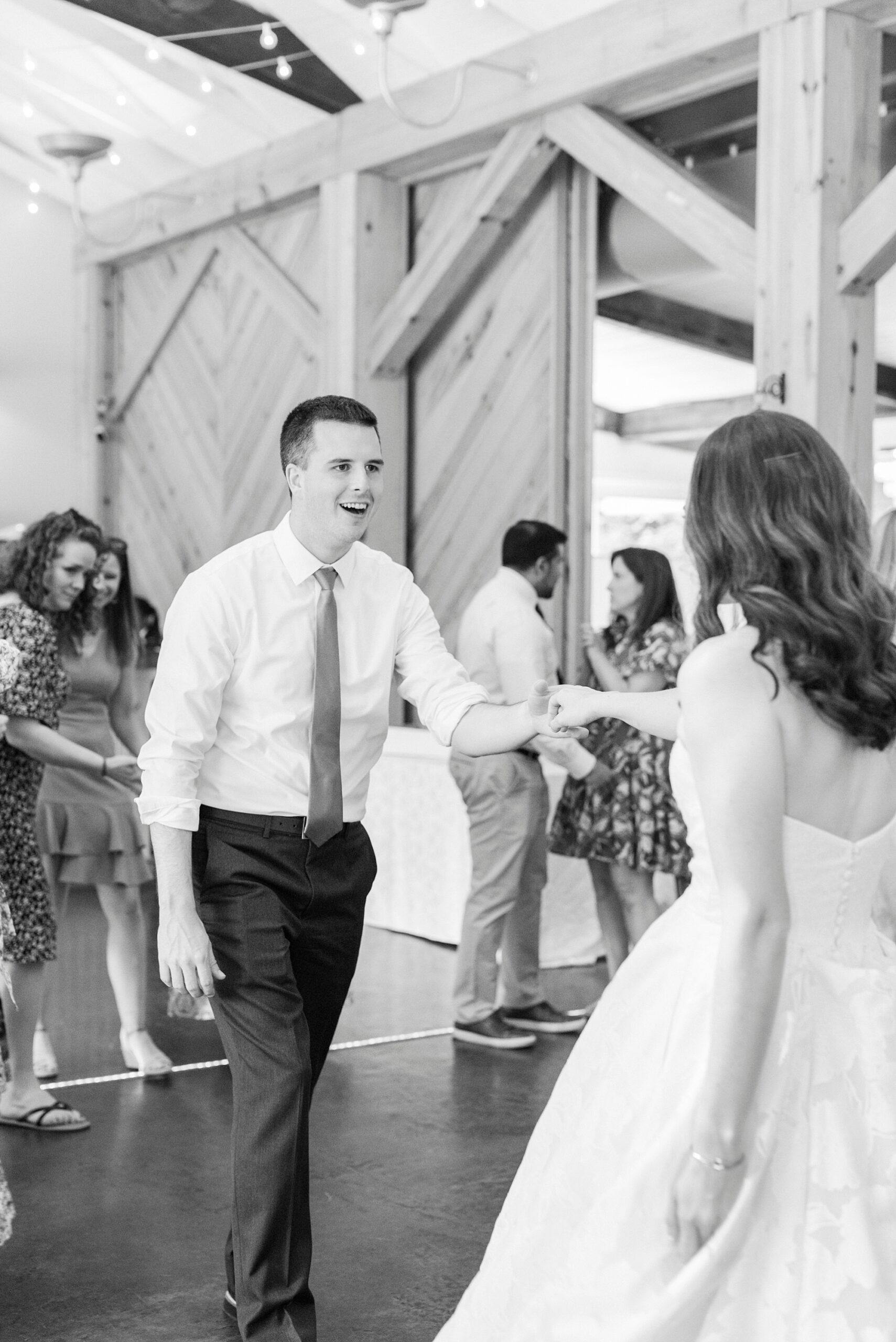 groom and bride dance during wedding reception in barn