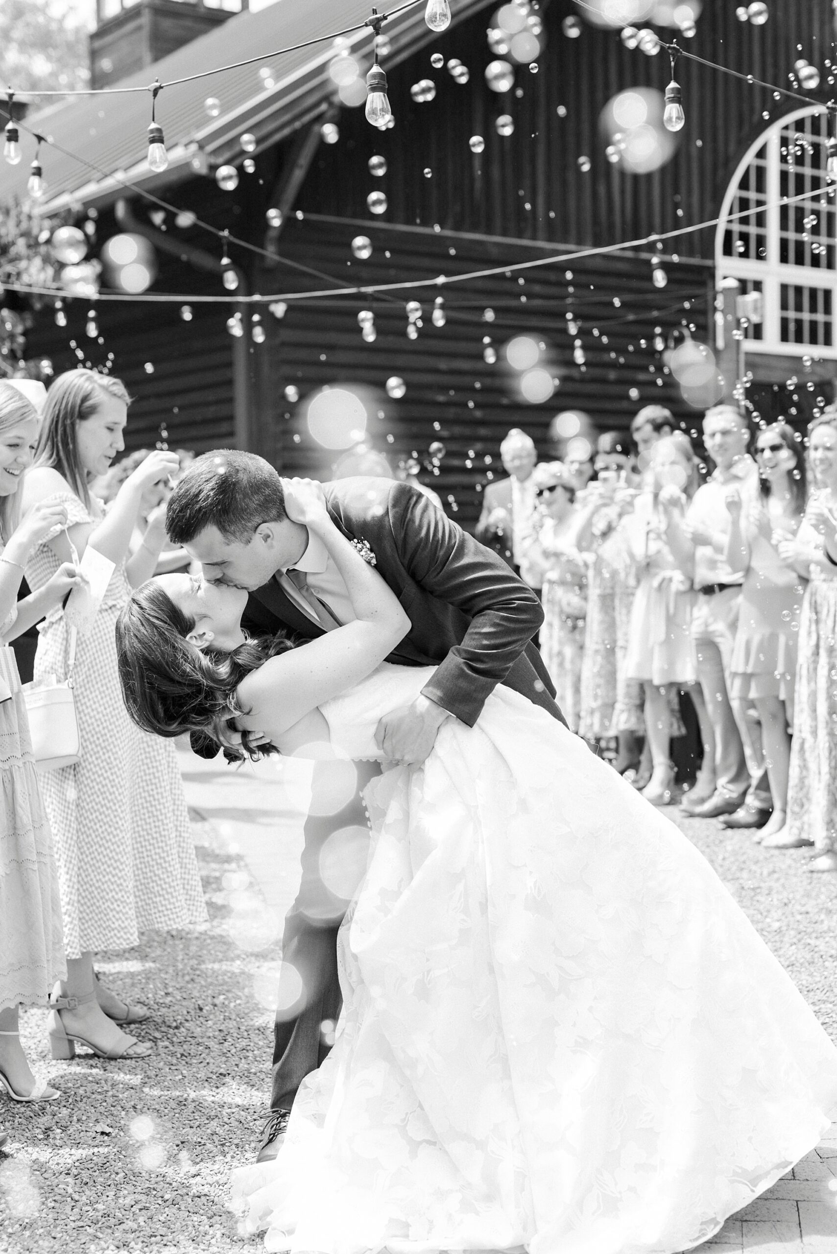 groom dips bride kissing her during bubble exit from brunch wedding