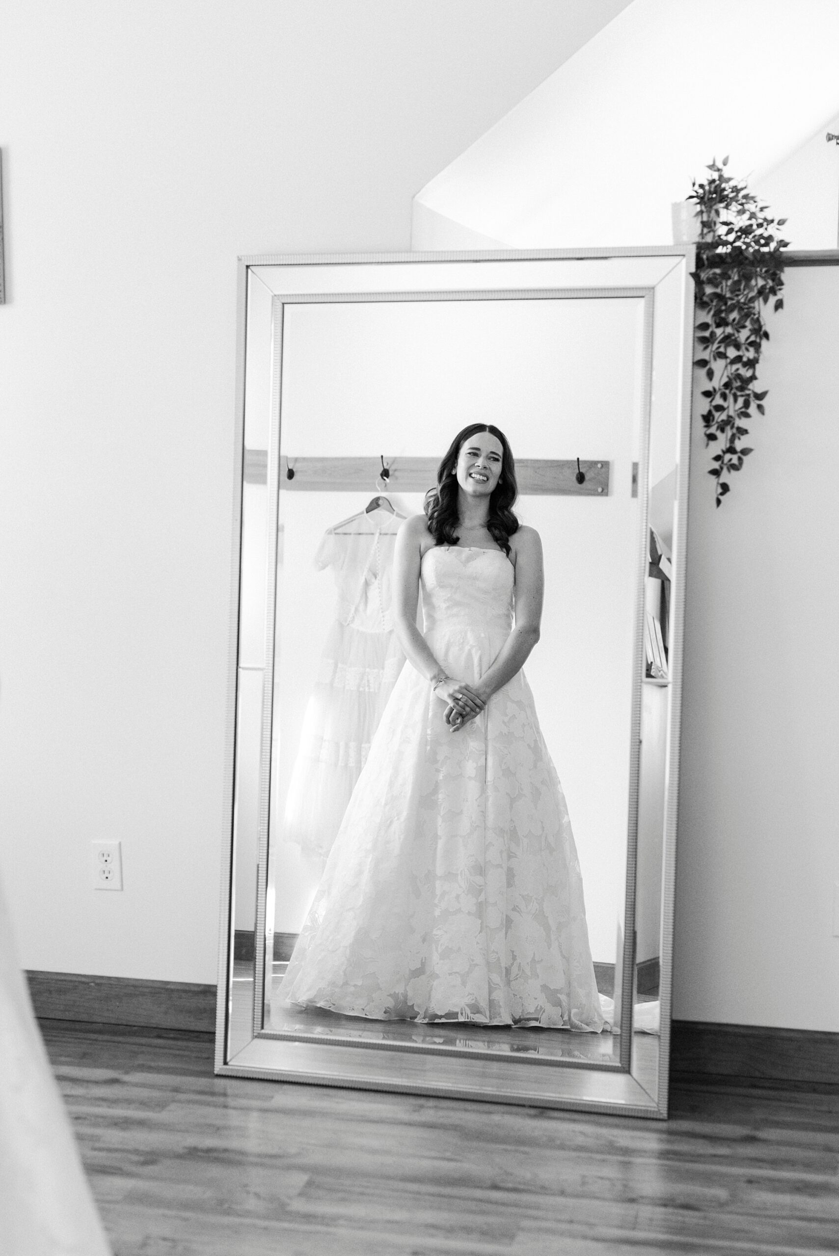 bride poses in front of mirror in strapless wedding gown