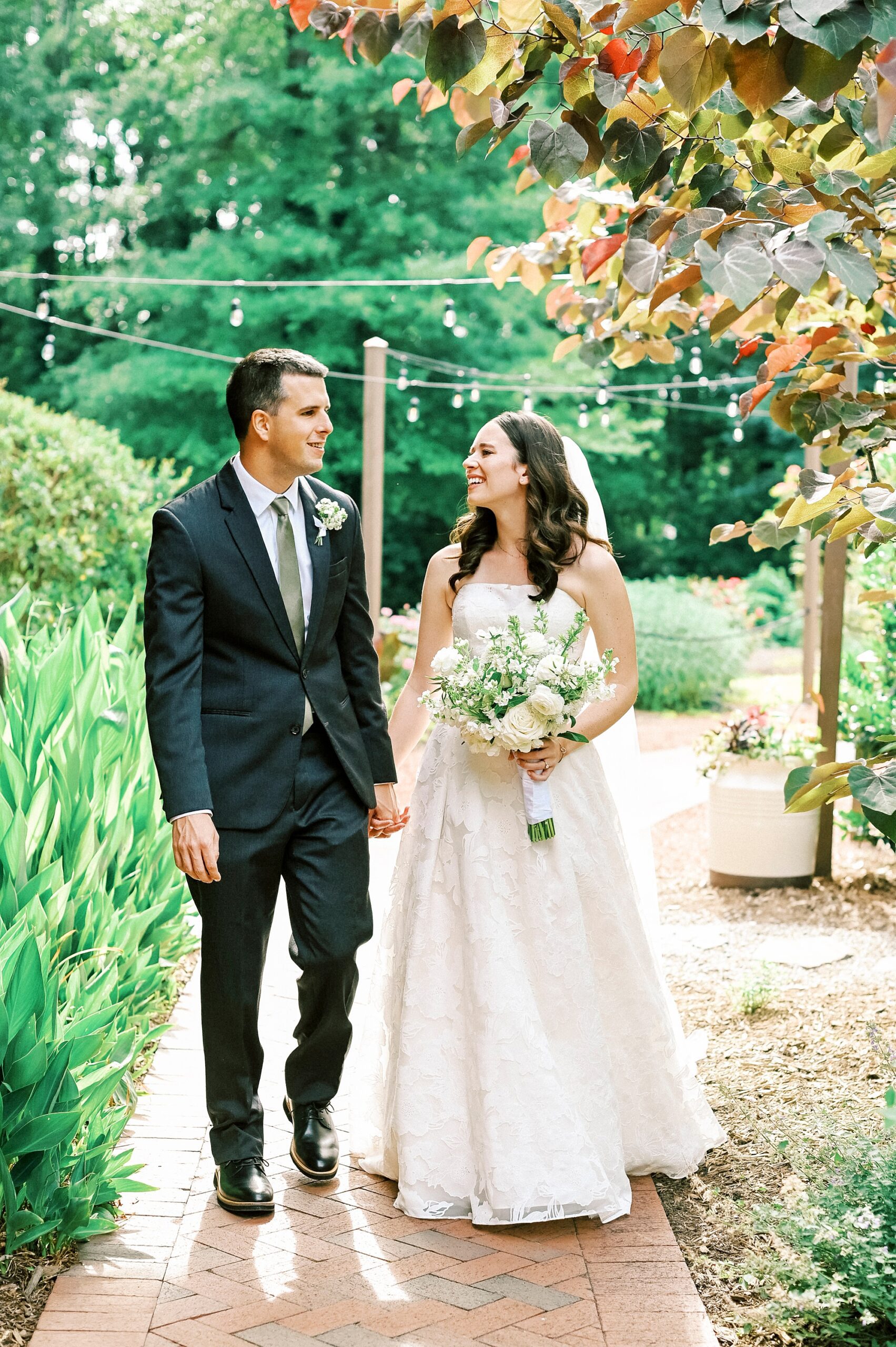 bride and groom smile walking together down path at Alexander Homestead