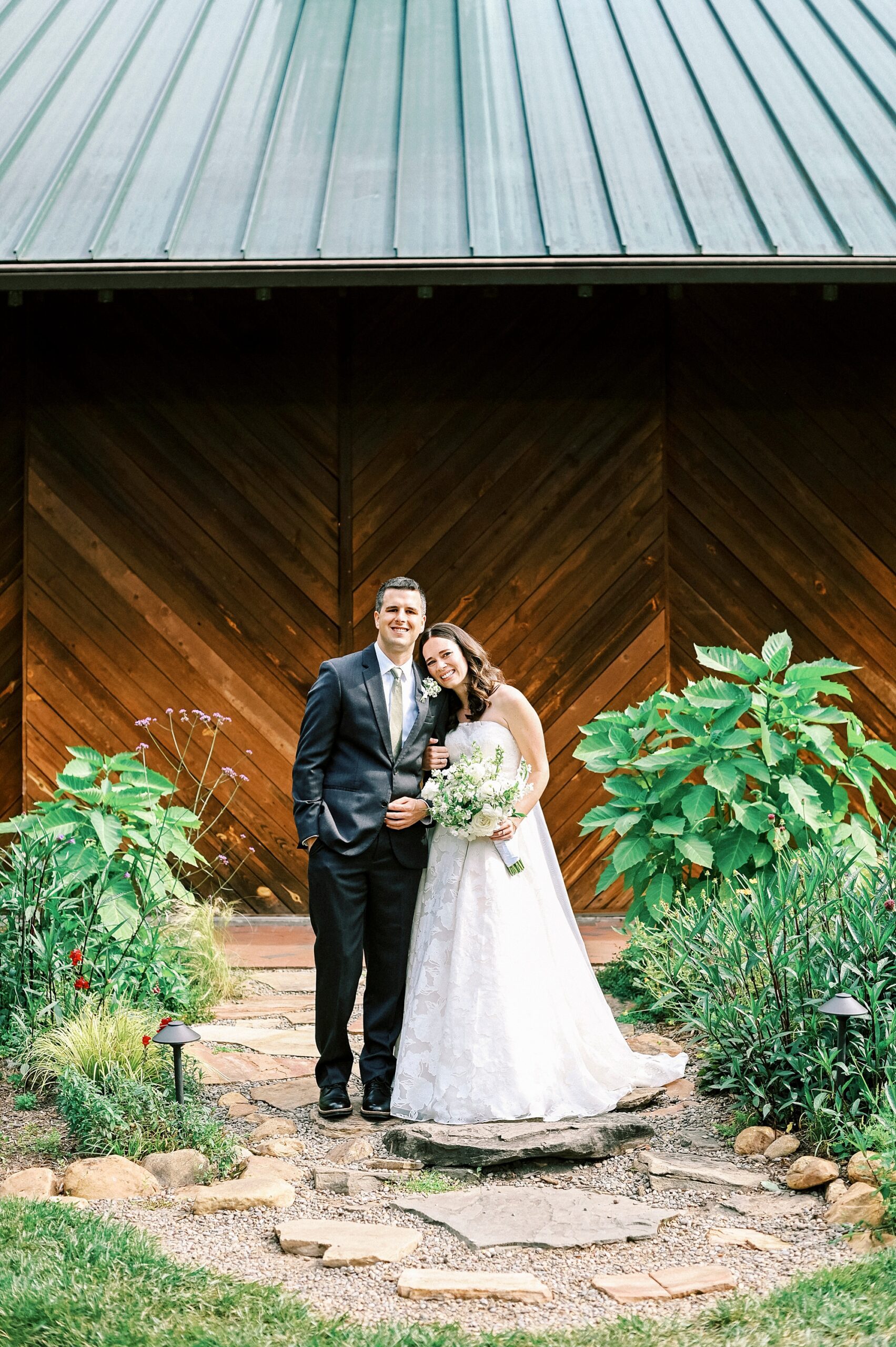 bride leans head on groom's shoulder outside wooden door